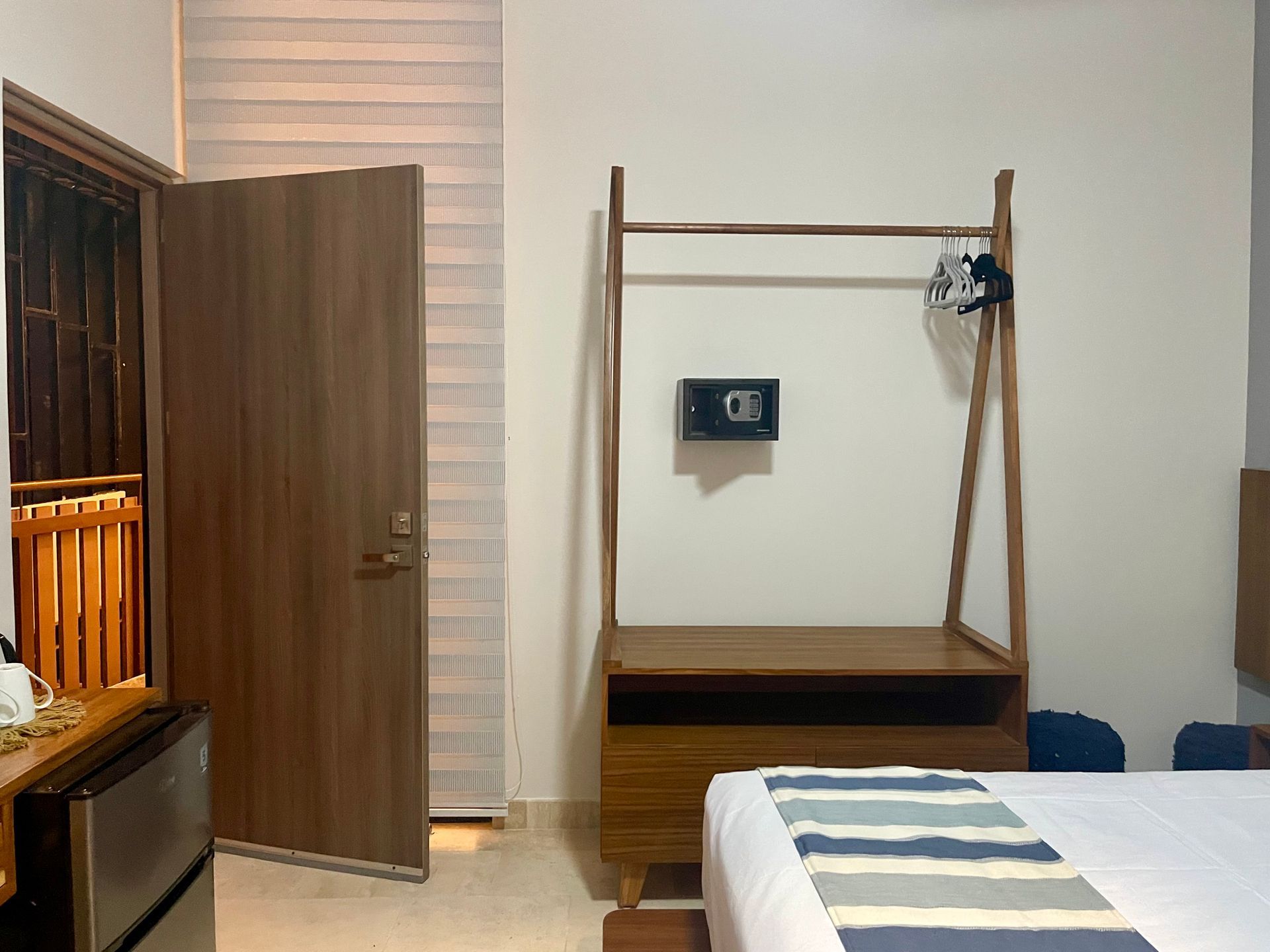 Habitación de hotel con muebles de madera, puerta abierta y cama.