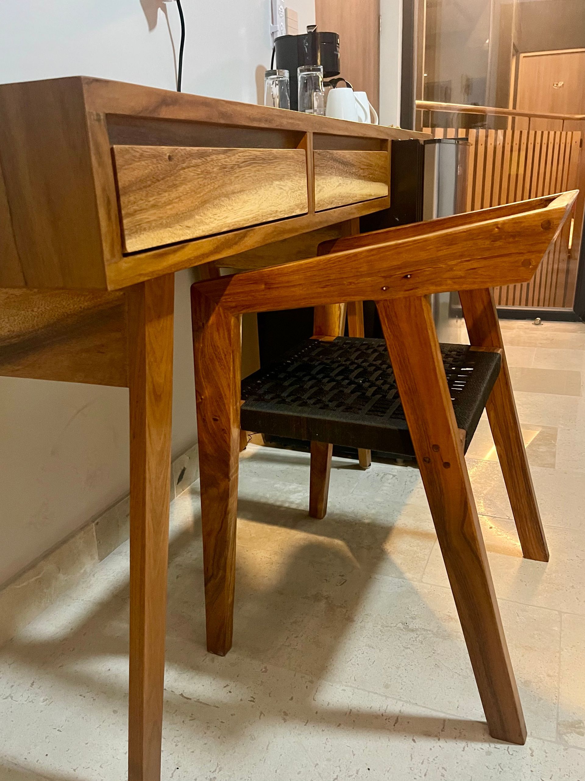 Escritorio y taburete de madera con cajón y asiento negro.