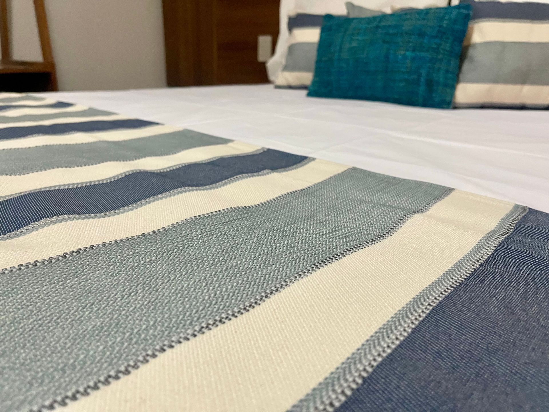 Camino de cama y almohadas de rayas azules y blancas sobre una cama.