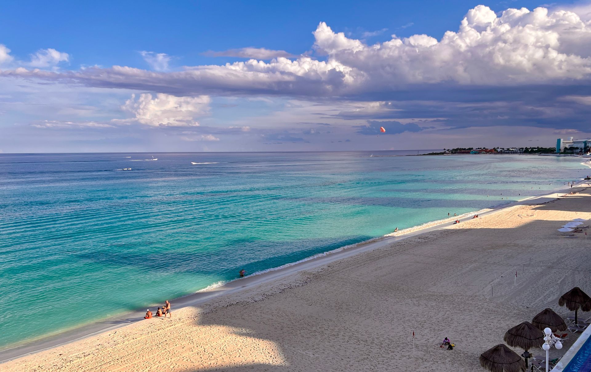 El océano turquesa se encuentra con una playa de arena blanca bajo un cielo azul nublado en Cancún.