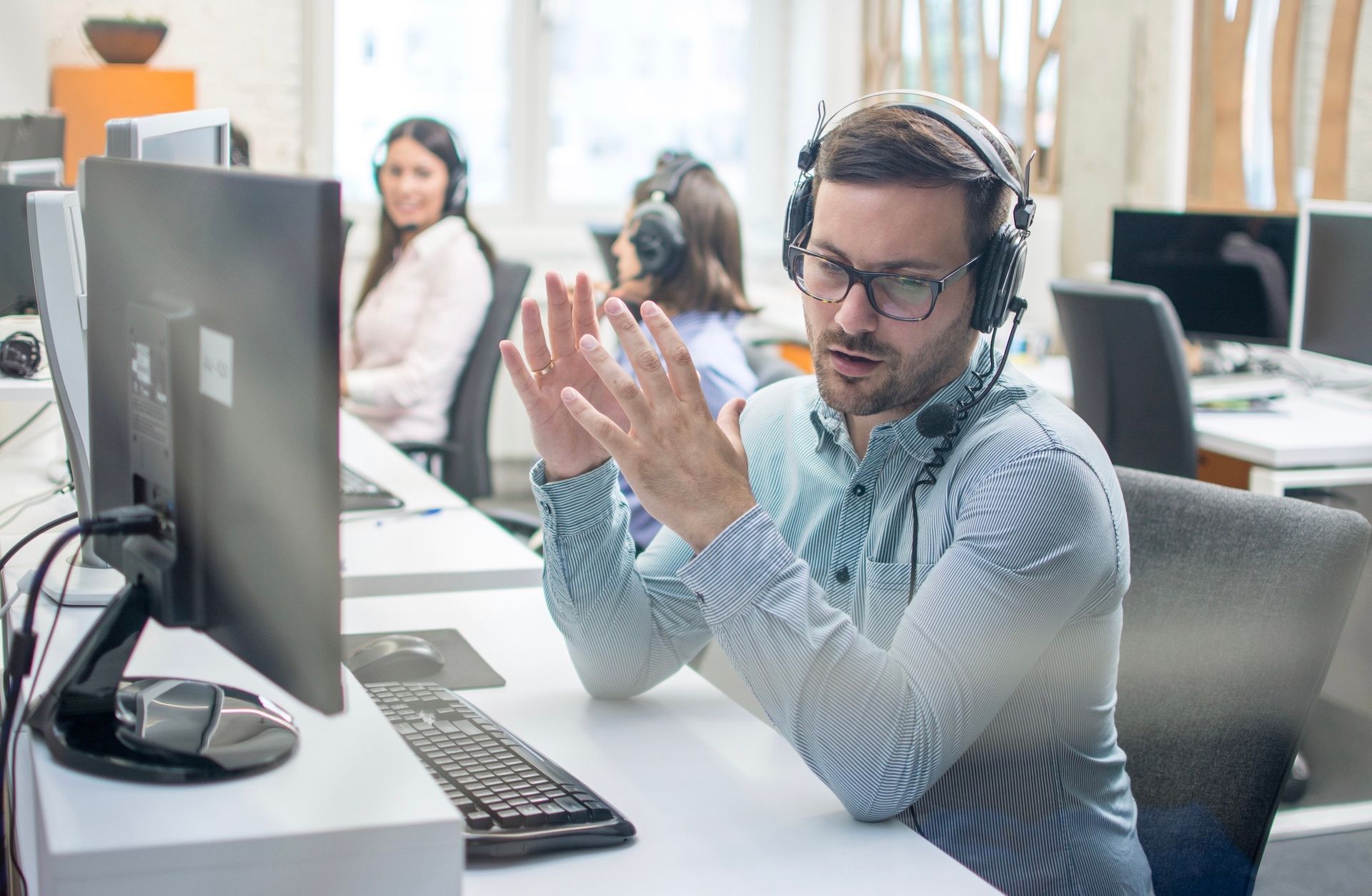 A man wearing headphones is sitting at a desk in front of a computer.