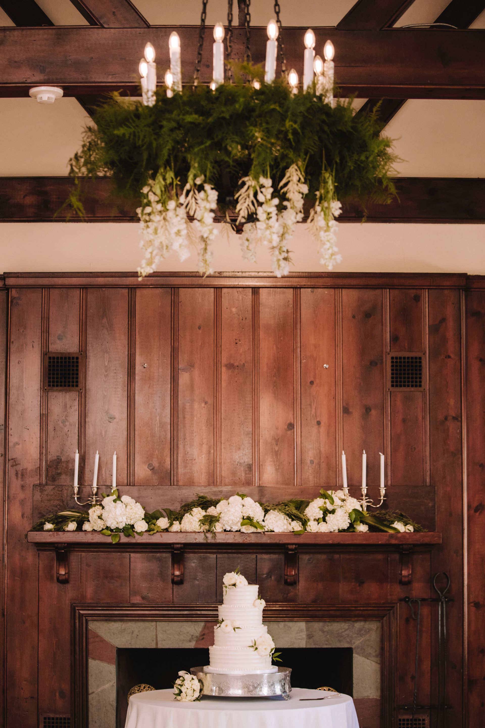 A wedding cake is sitting on a table in front of a fireplace.