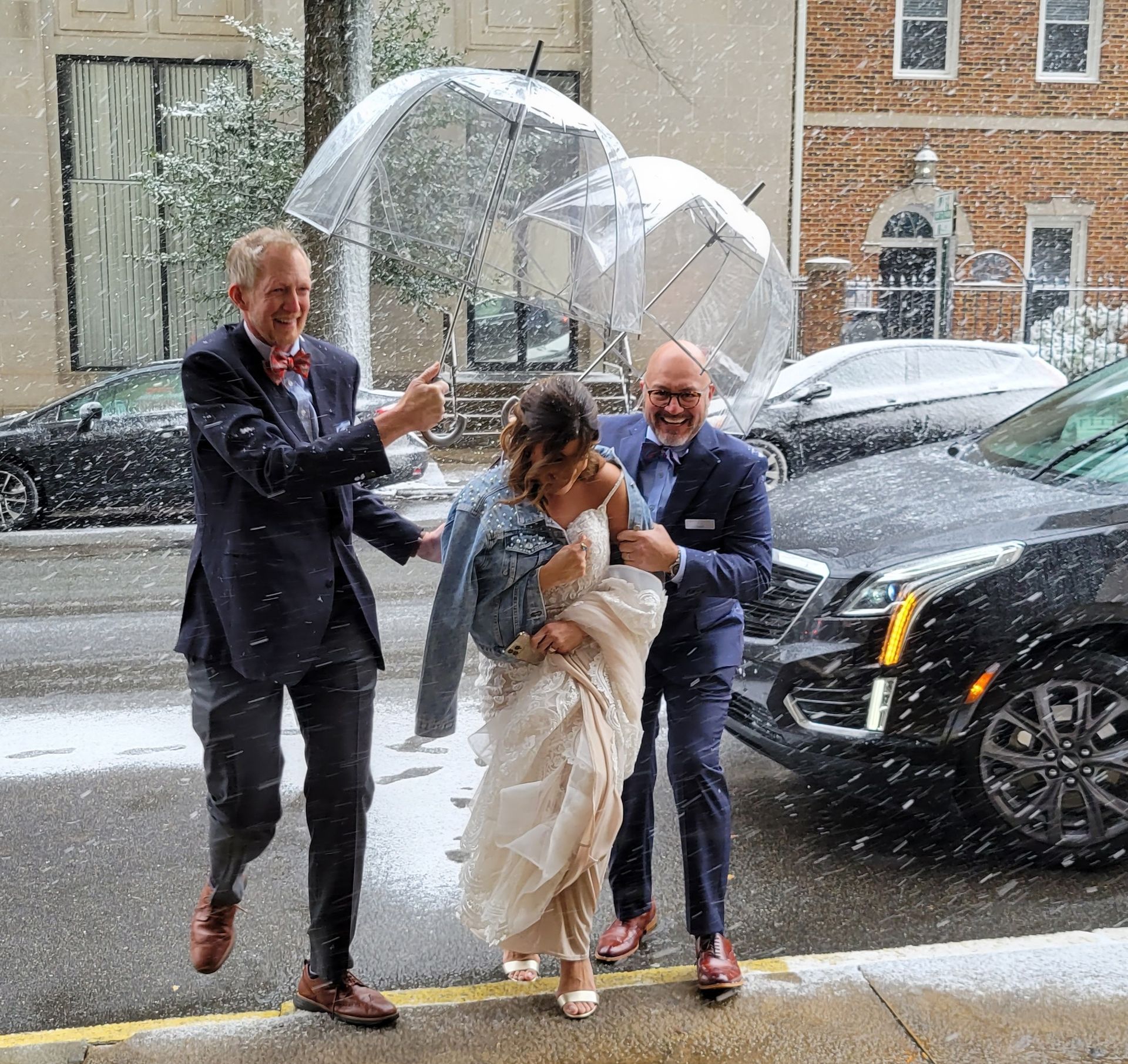 A bride and groom are walking down the street in the rain holding umbrellas.