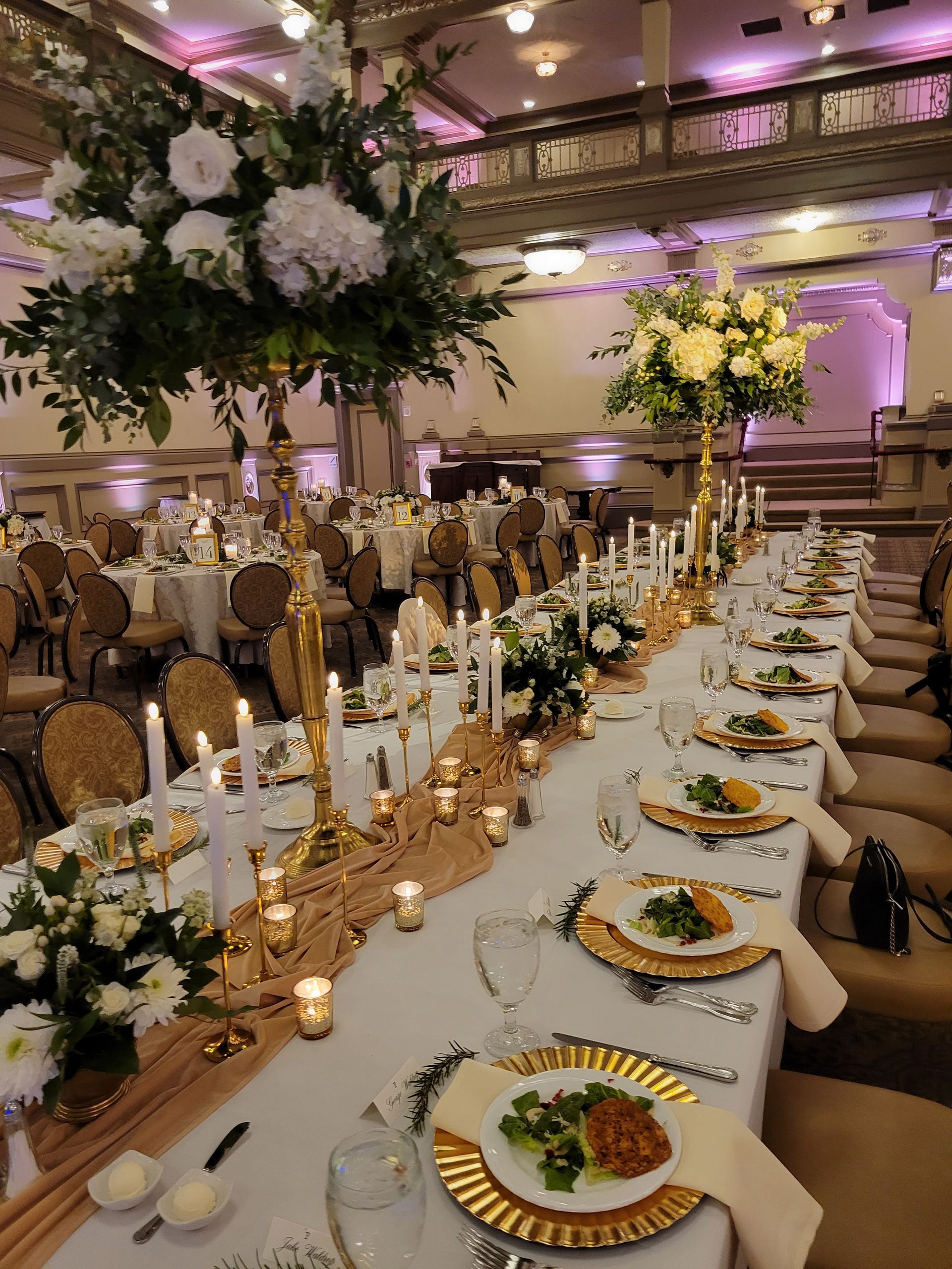A long table with plates of food and candles on it in a large room.