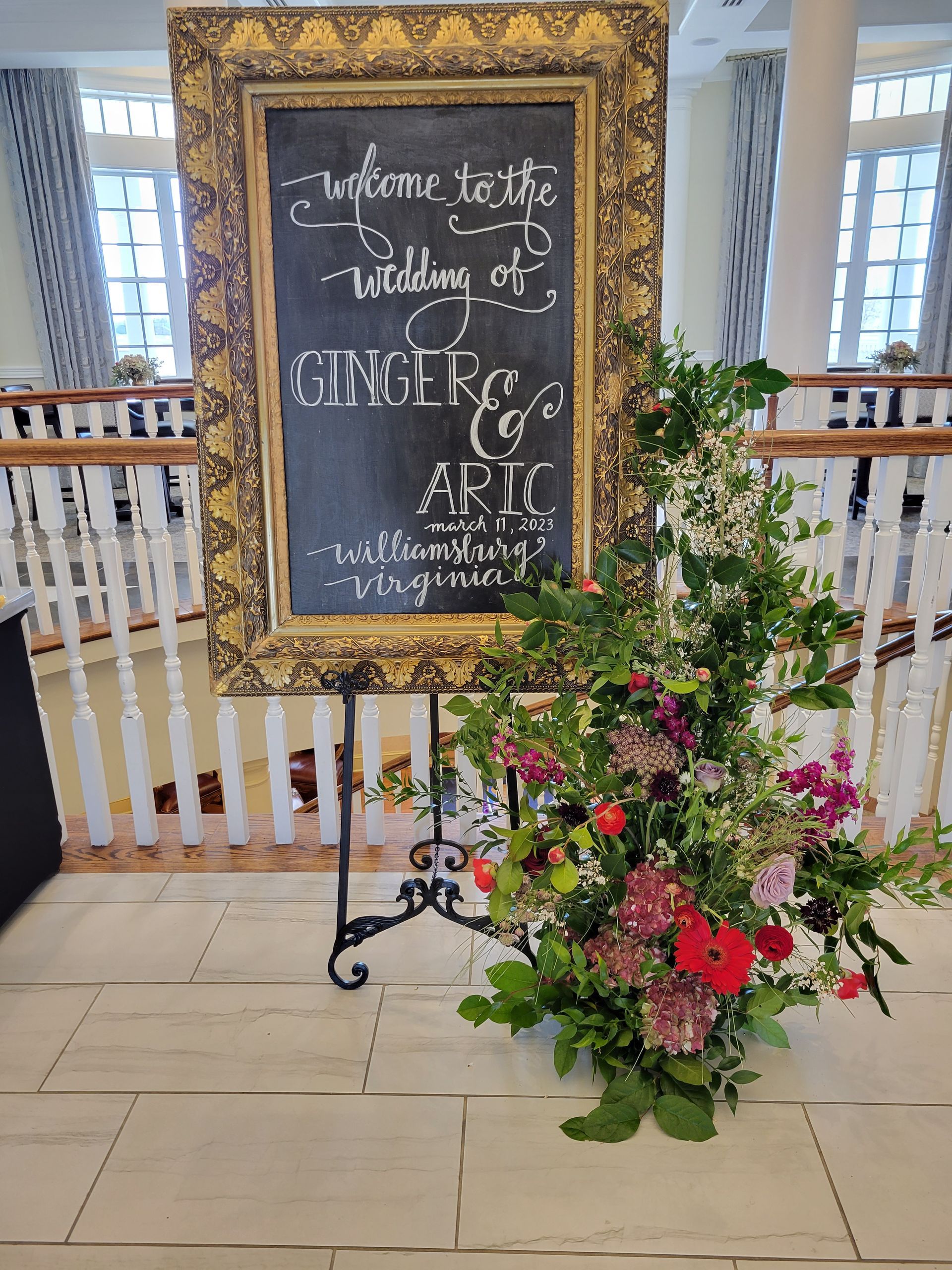 A large chalkboard with flowers in front of it.