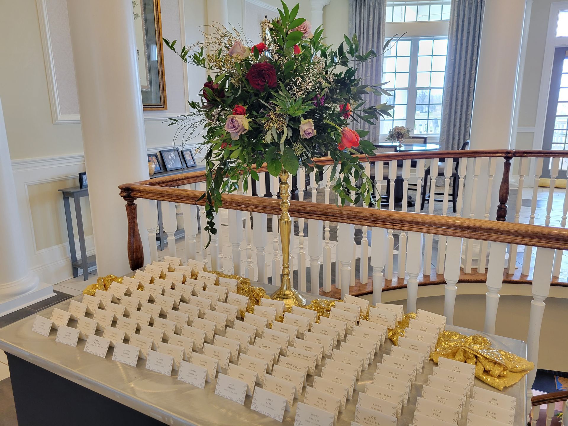 A table with lots of name cards and a vase of flowers on it.