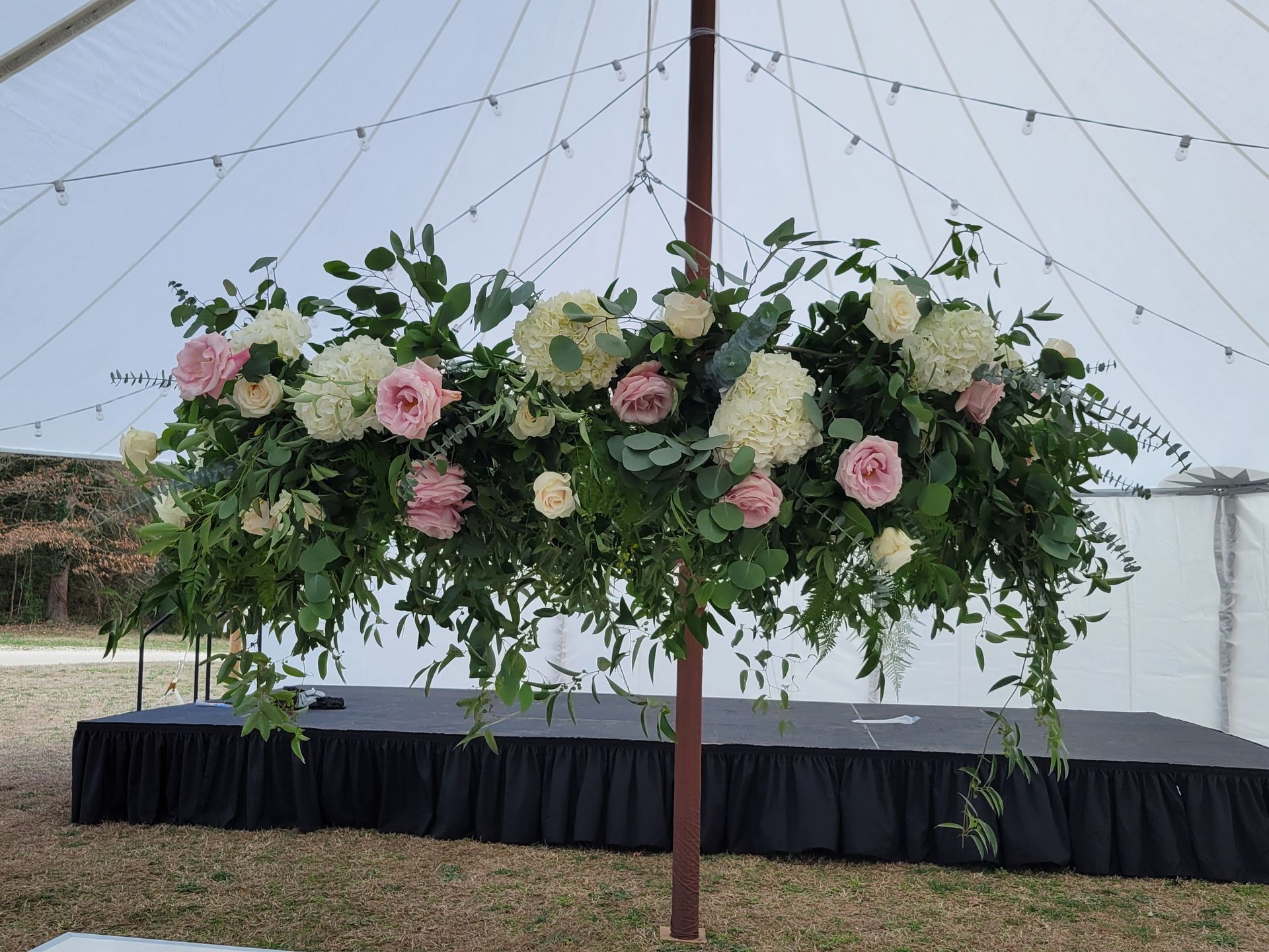 A large floral arrangement is hanging from the side of a tent.