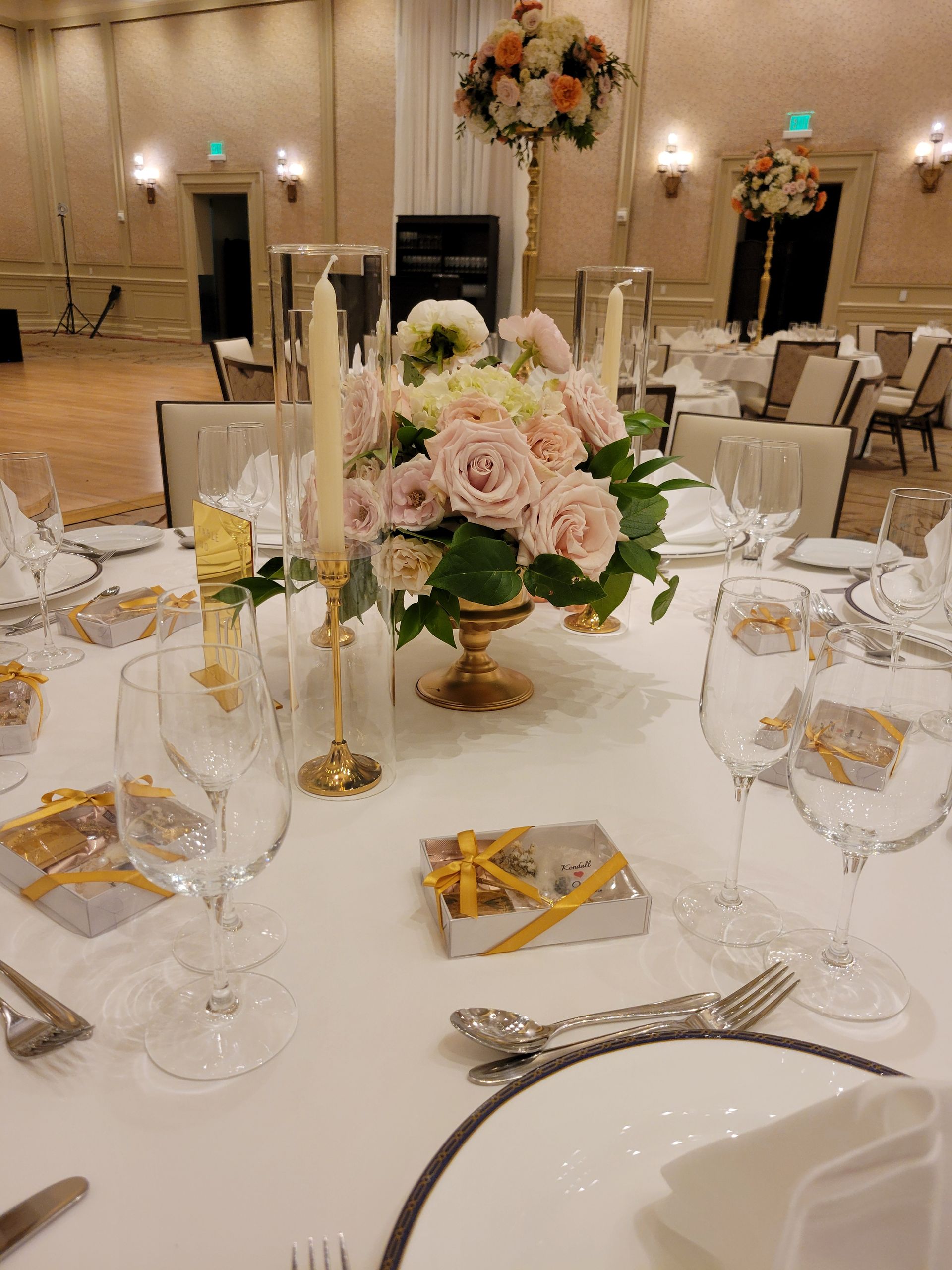 A table set for a wedding reception with a vase of flowers on it.
