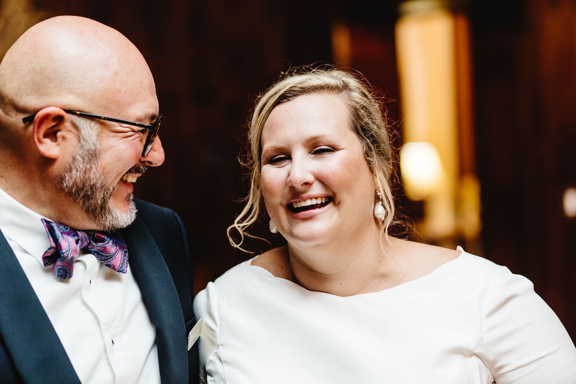 A man and a woman are laughing together and looking at each other.