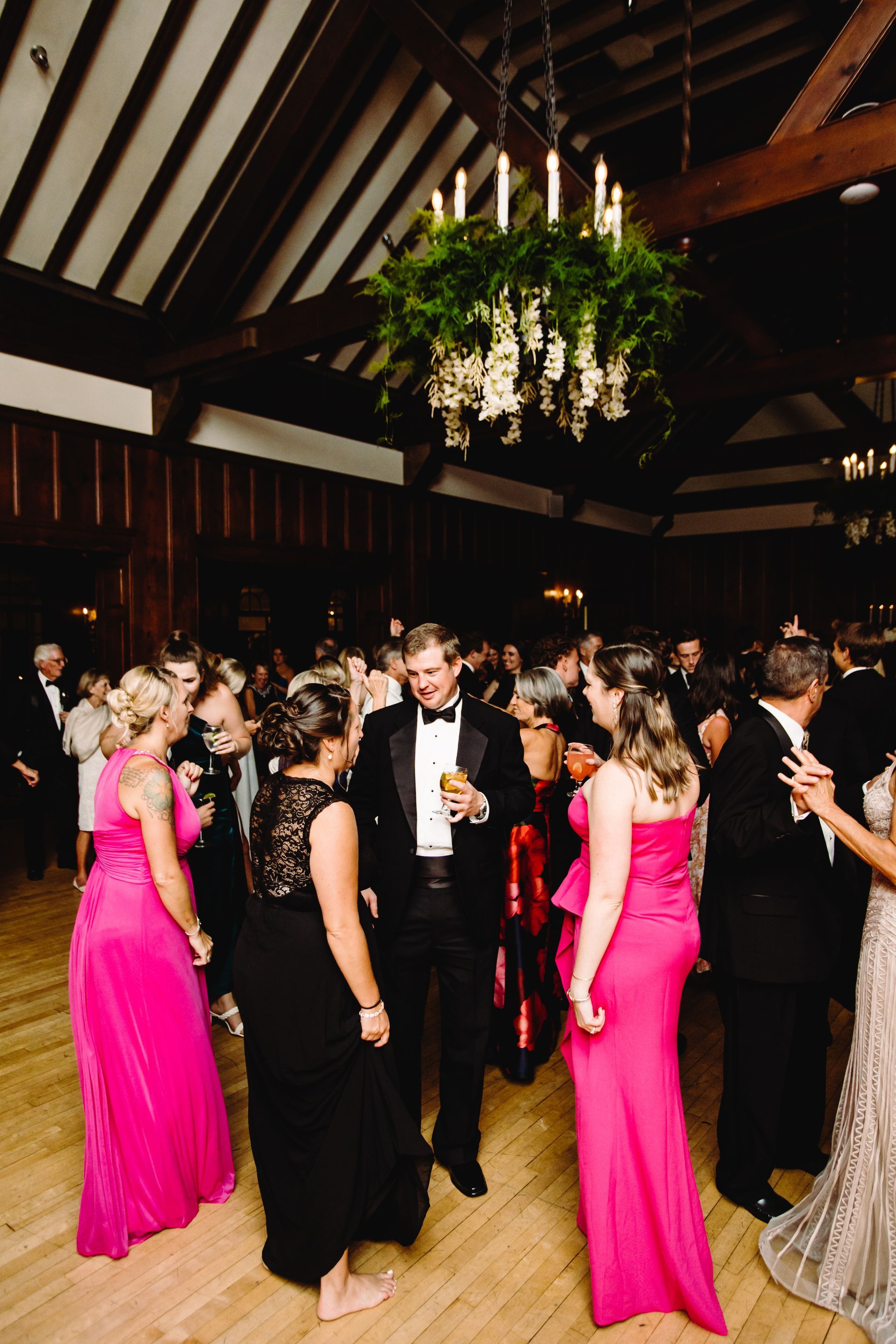 A group of people are dancing in a room with a chandelier hanging from the ceiling.
