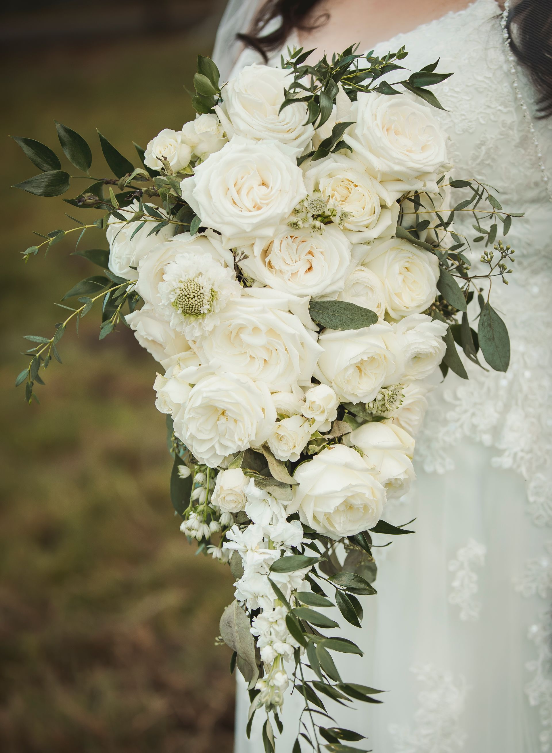 A bride in a white dress is holding a bouquet of white flowers.