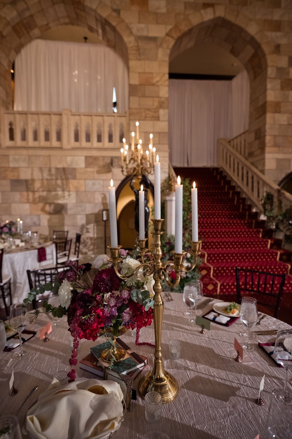 A table set for a wedding reception with candles and flowers on it.