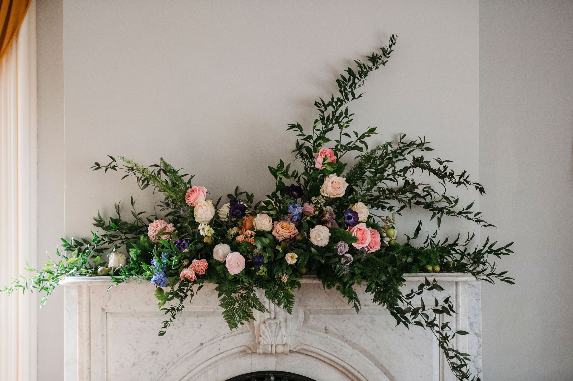 A fireplace with flowers and greenery on it.
