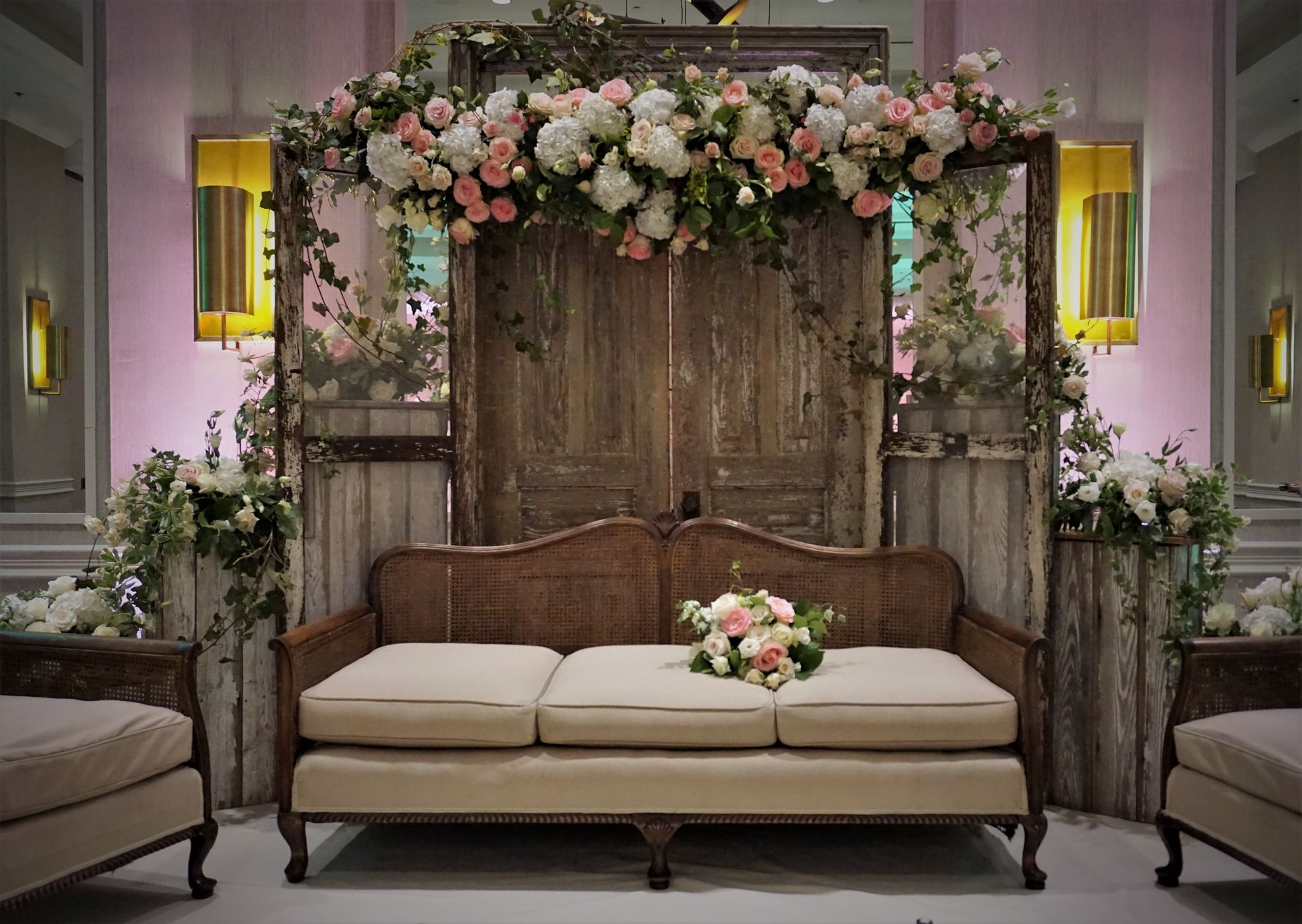 A couch is sitting in front of a wooden door decorated with flowers.