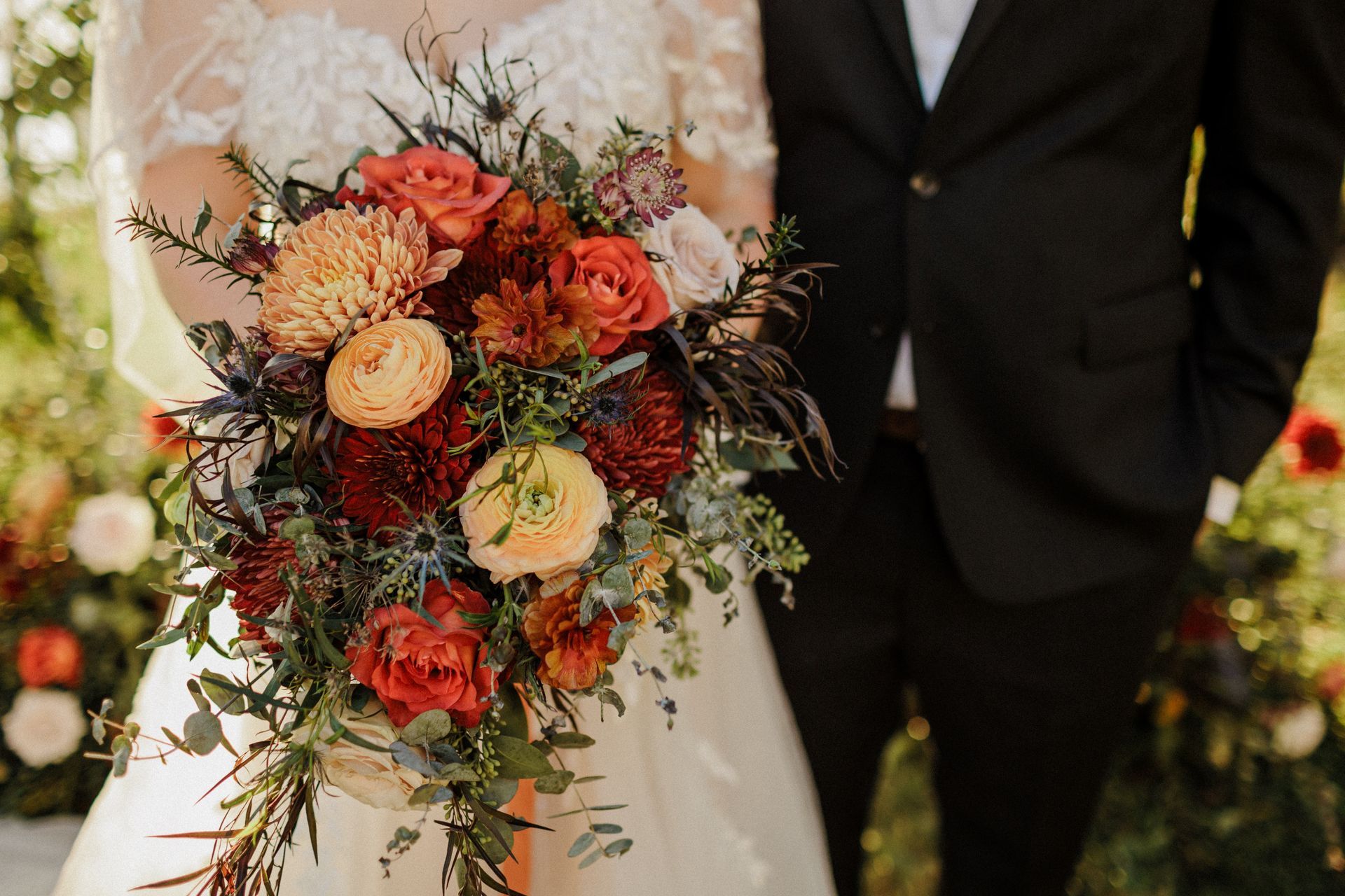 A bride and groom are standing next to each other holding a bouquet of flowers.