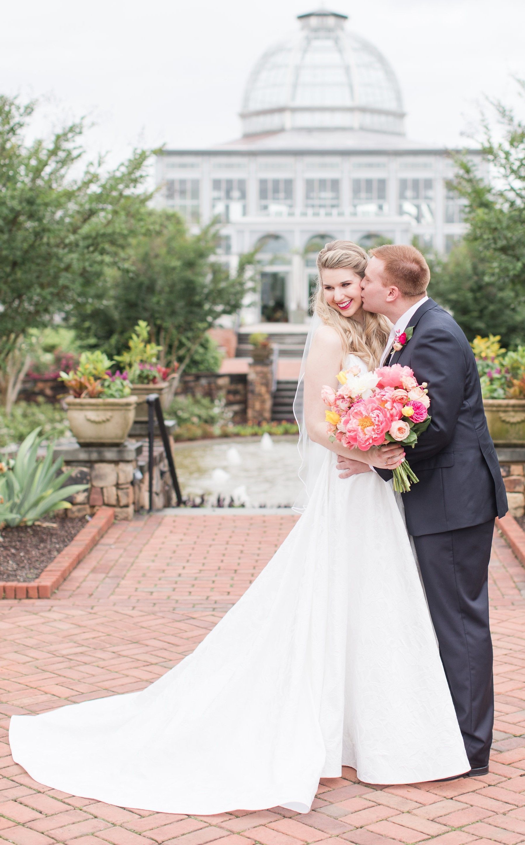 A bride and groom are kissing in front of a building.