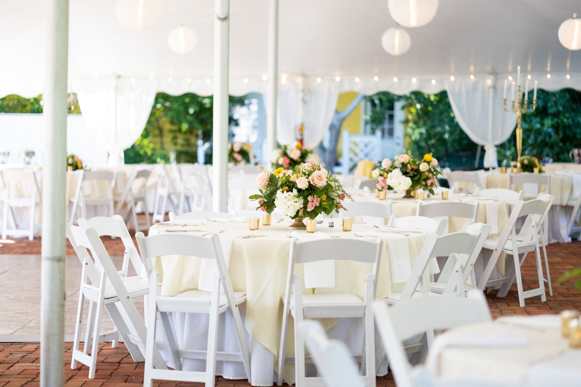 Tables and chairs are set up under a tent for a wedding reception.