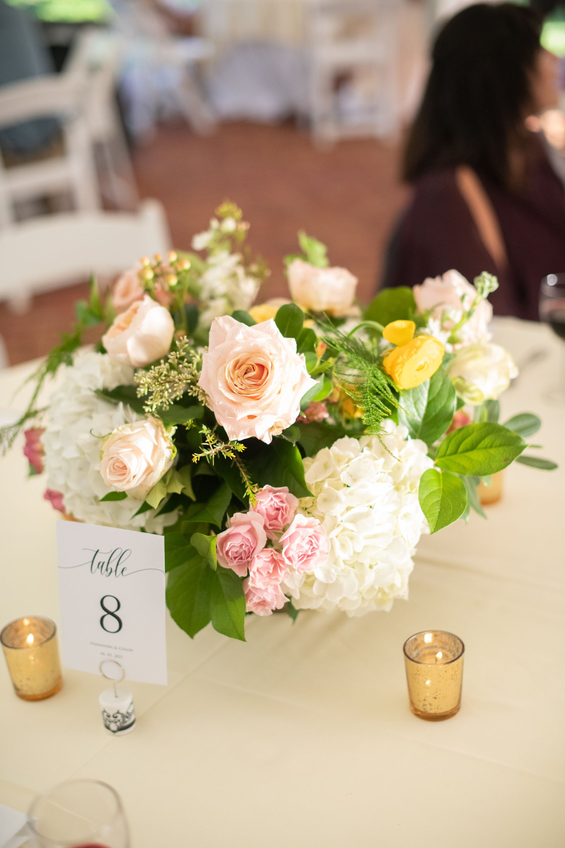 A table with a vase of flowers and candles on it.