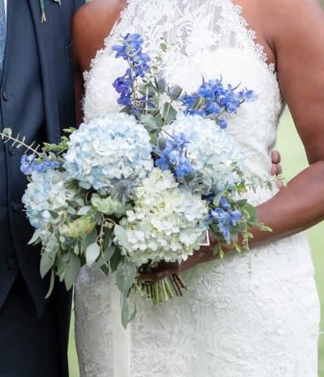 The bride is holding a bouquet of blue and white flowers