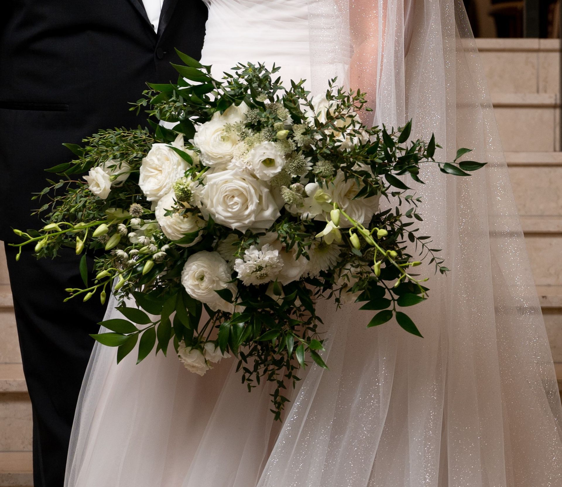 The bride is holding a bouquet of white flowers