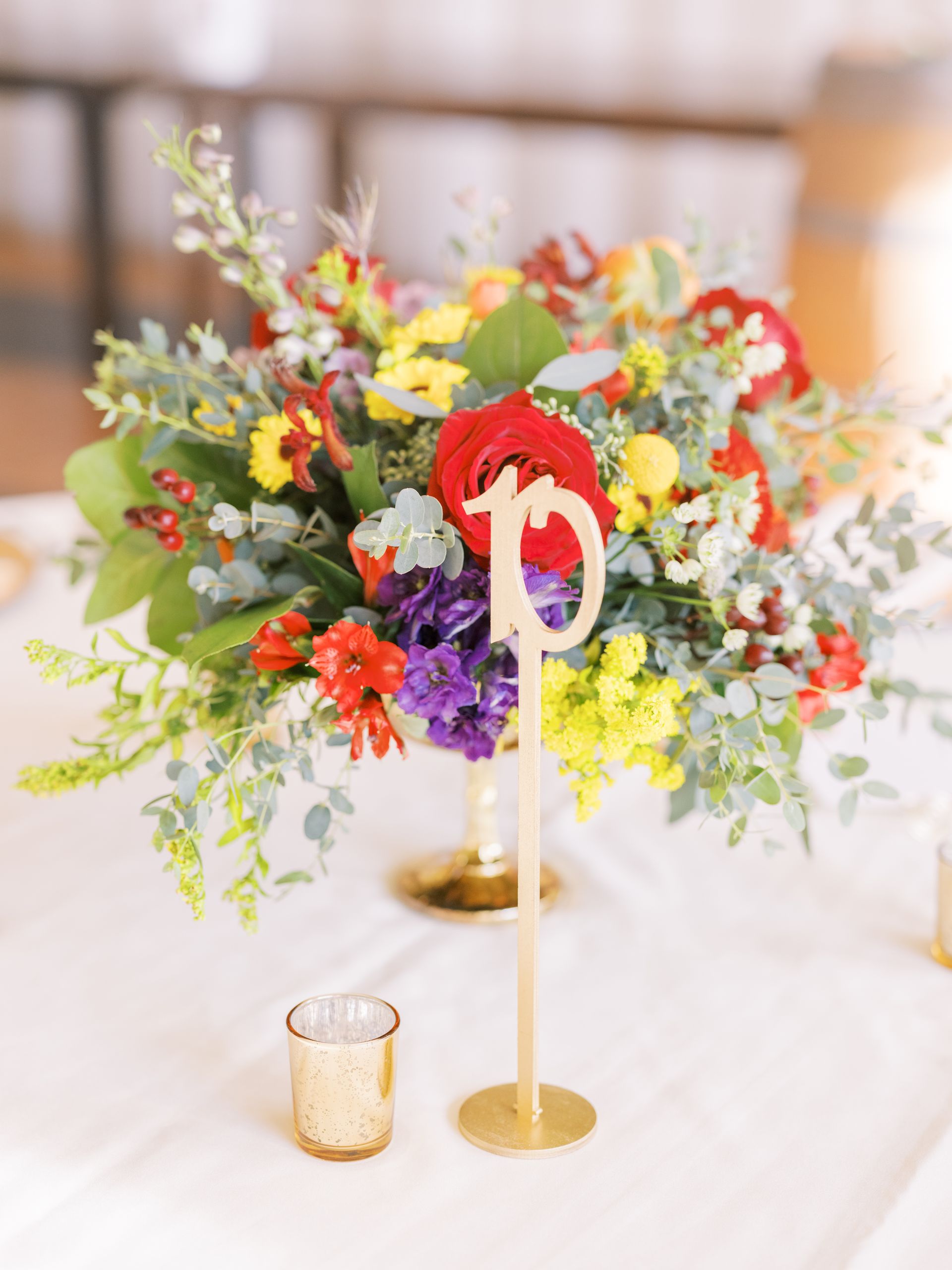 A table with a vase of flowers and a table number on it.