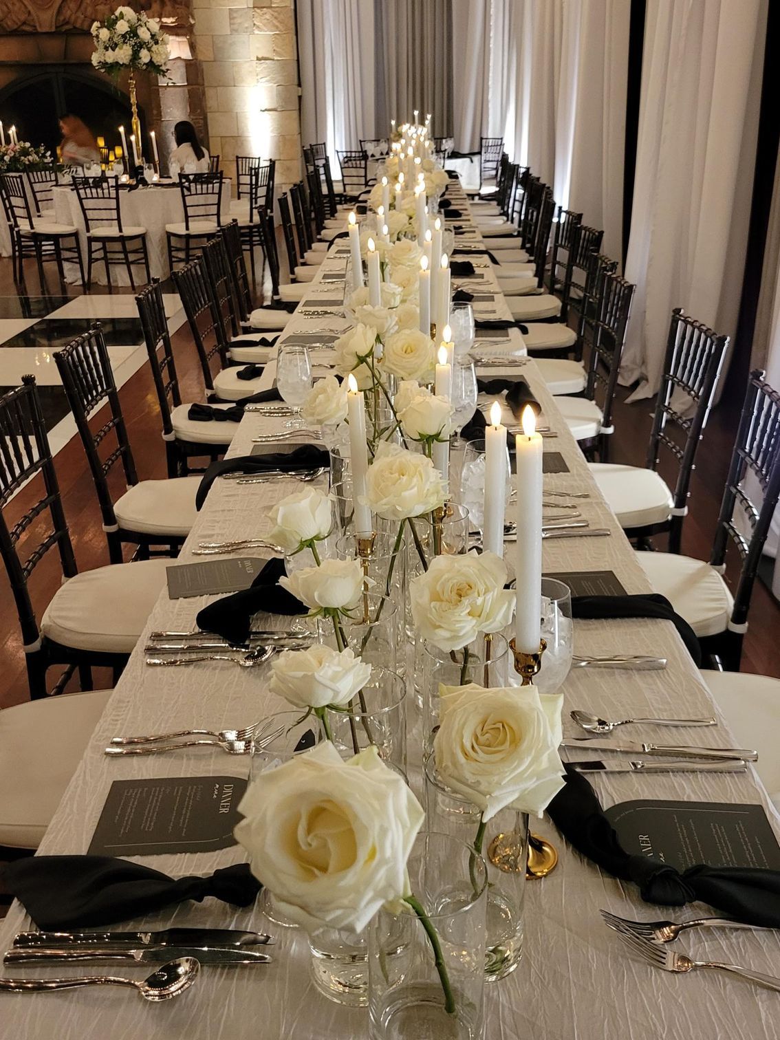 A long table set for a wedding reception with white roses and candles.