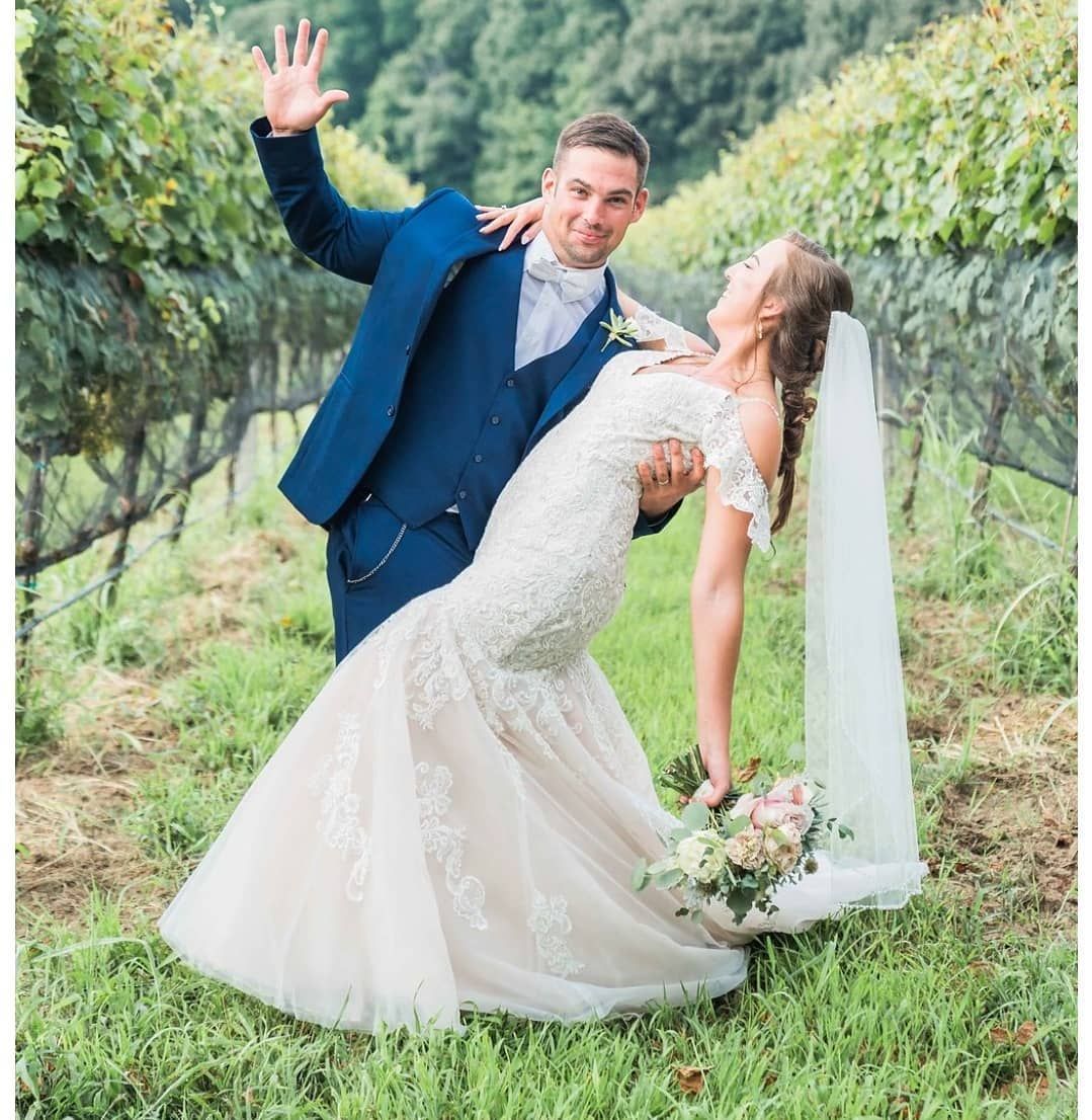 A bride and groom are posing for a picture in a vineyard.