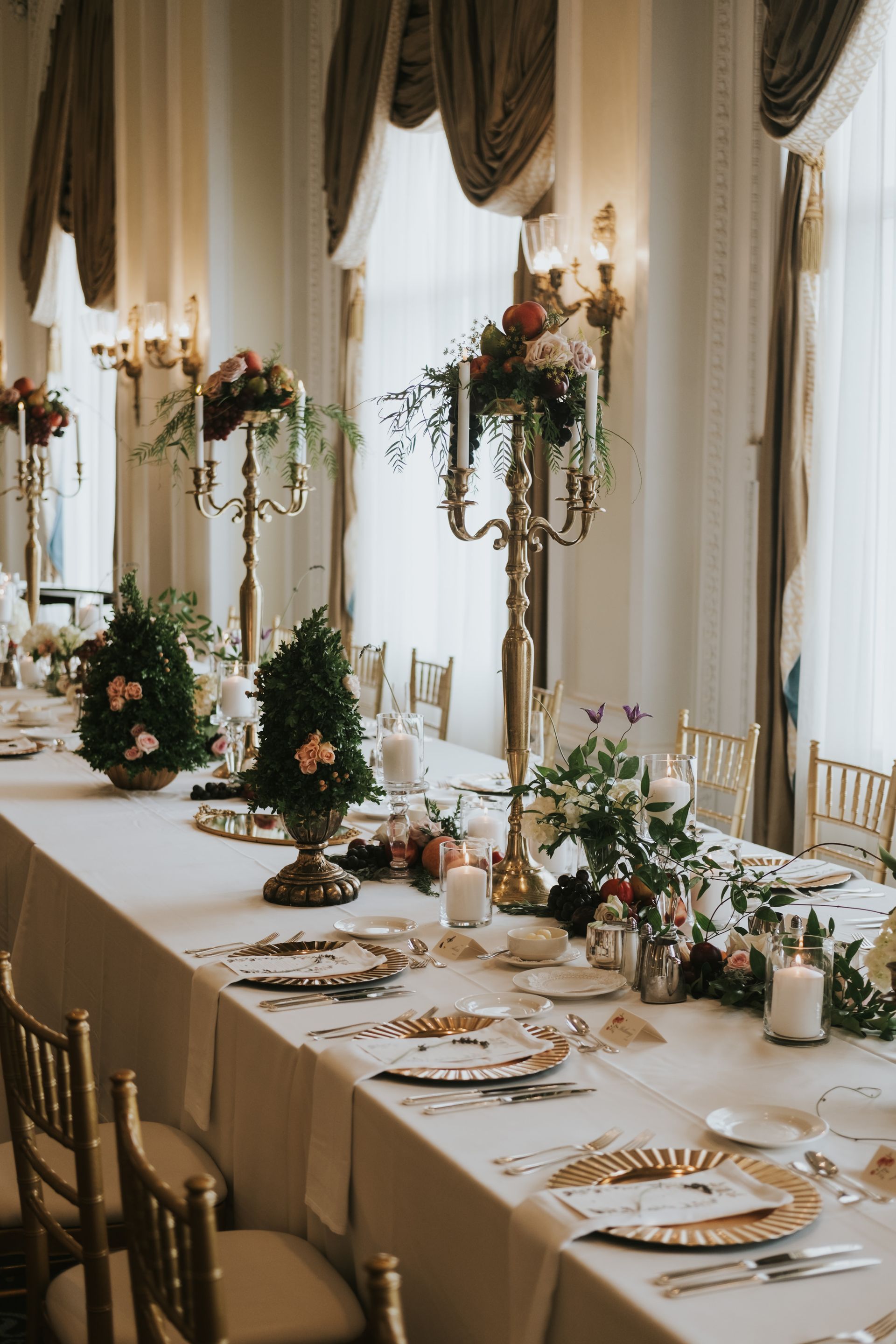 A long table with plates , candles , and flowers on it.