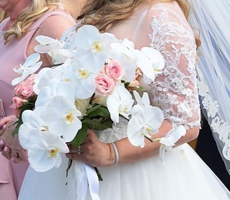 A woman in a wedding dress is holding a bouquet of white flowers.