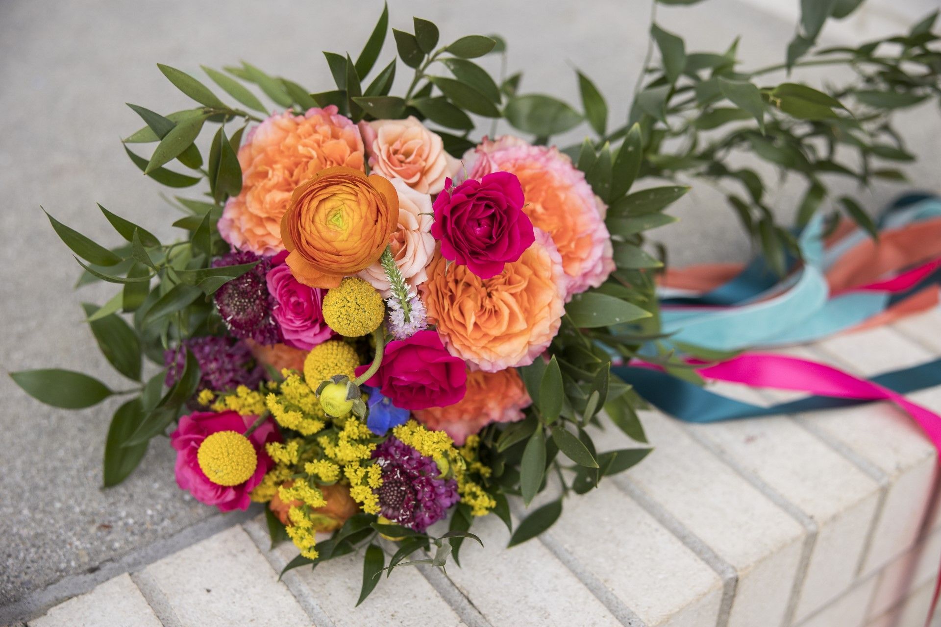 A colorful bouquet of flowers is sitting on a brick wall.