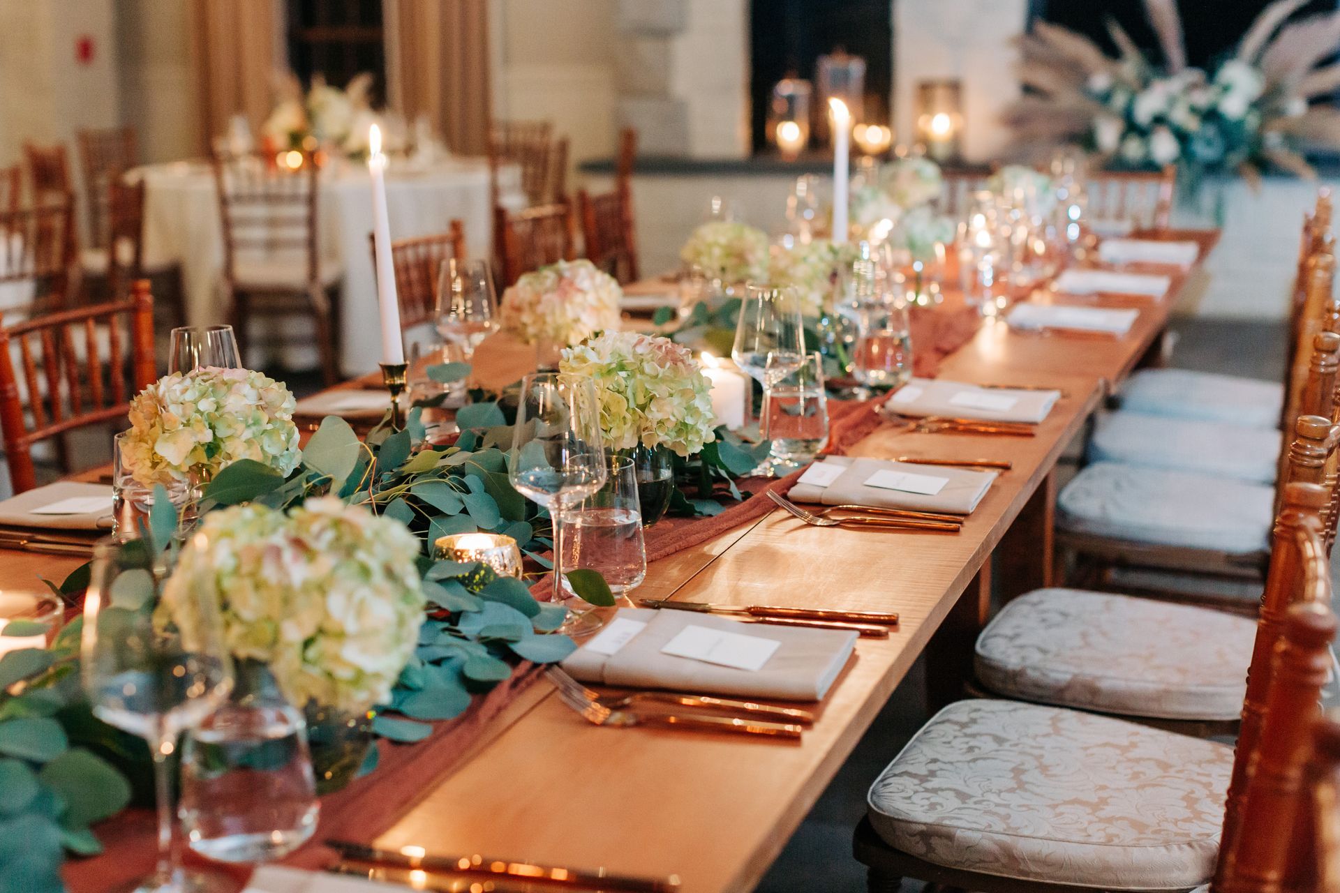 A long wooden table with flowers and candles on it.