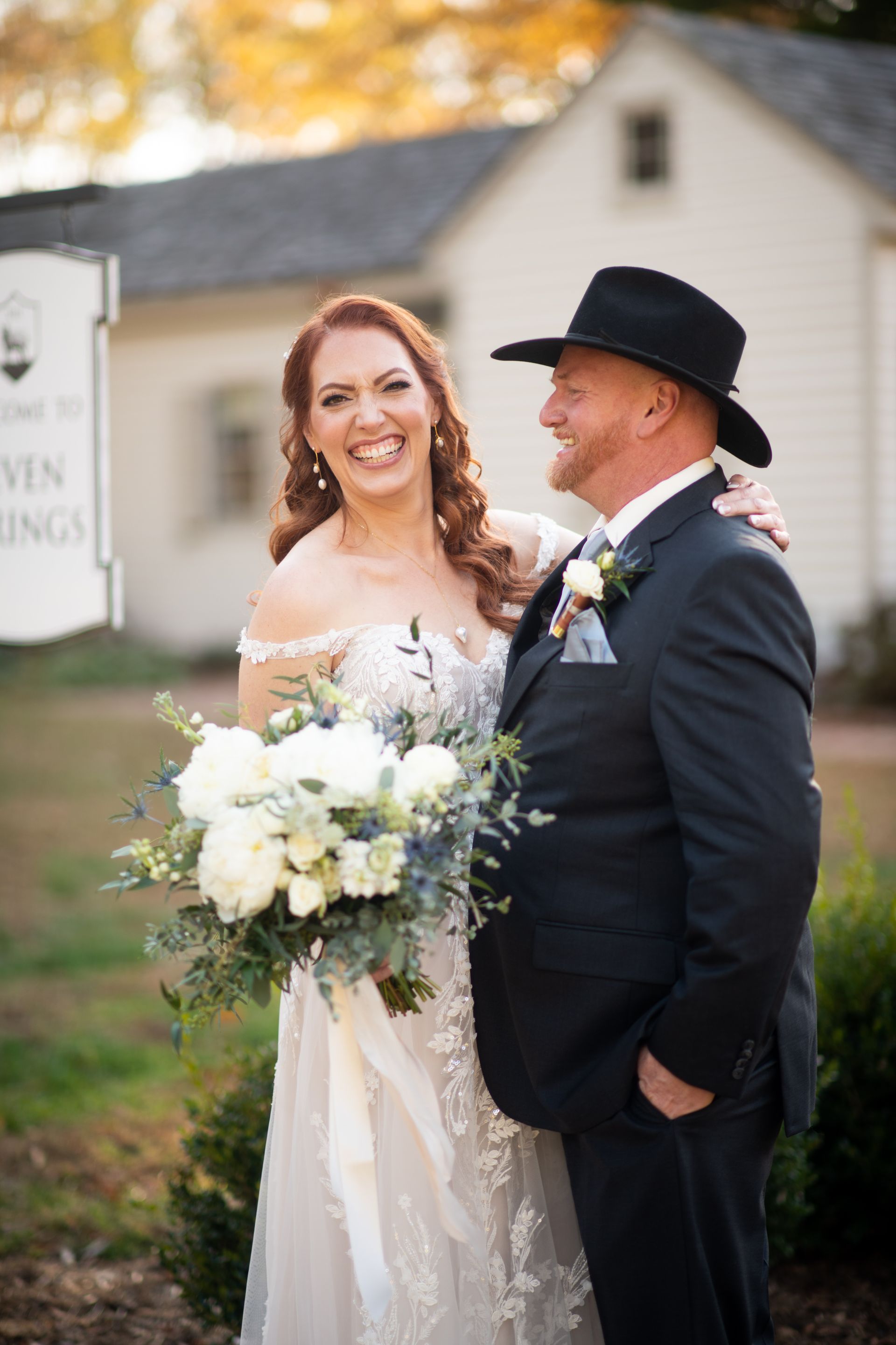 A bride and groom are posing for a picture in front of a white building.
