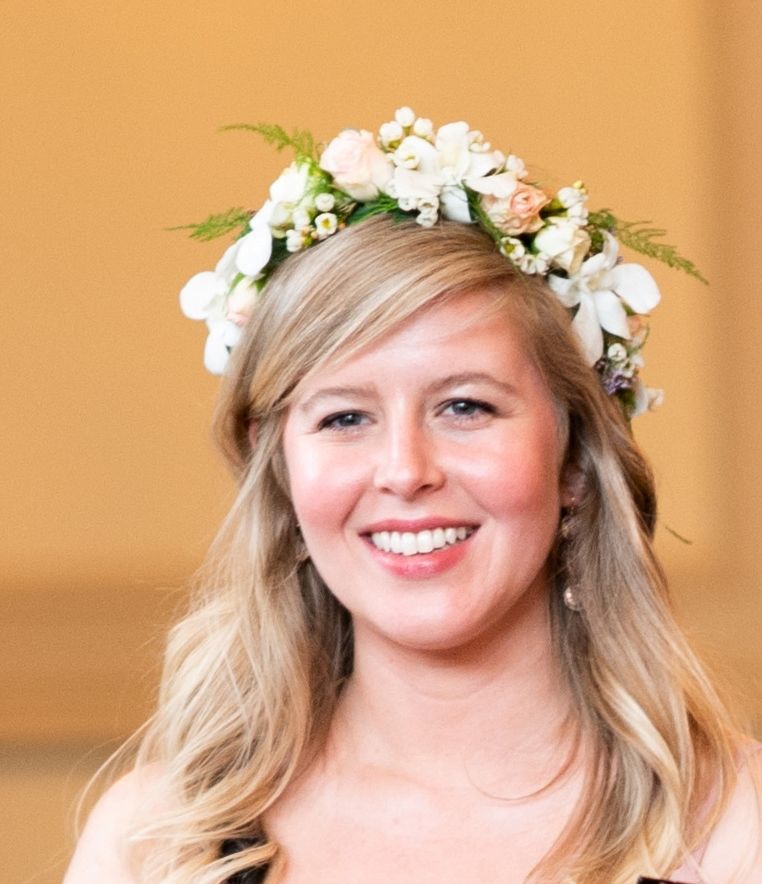 A woman wearing a flower crown is smiling for the camera