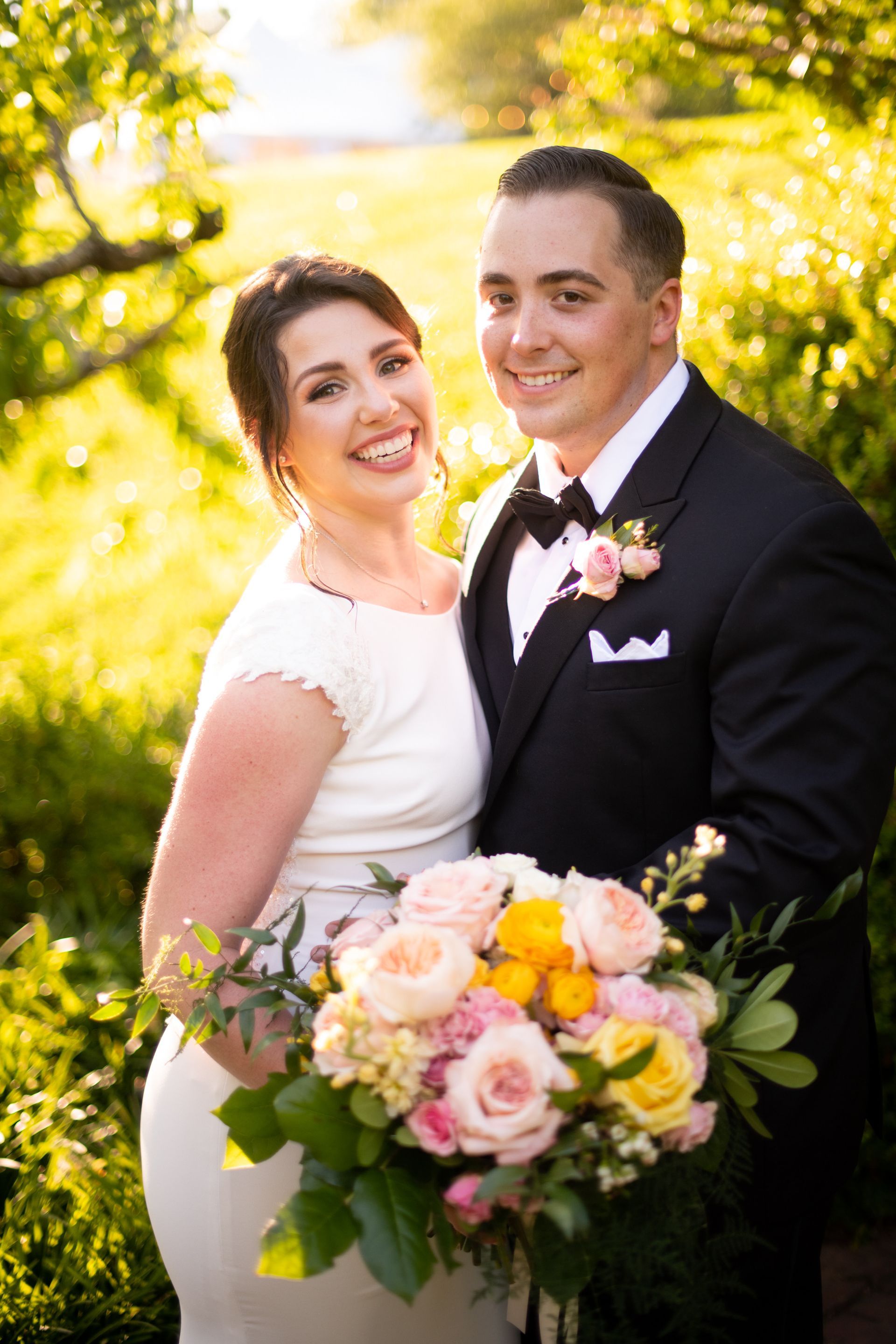 A bride and groom are posing for a picture while the bride is holding a bouquet of flowers.
