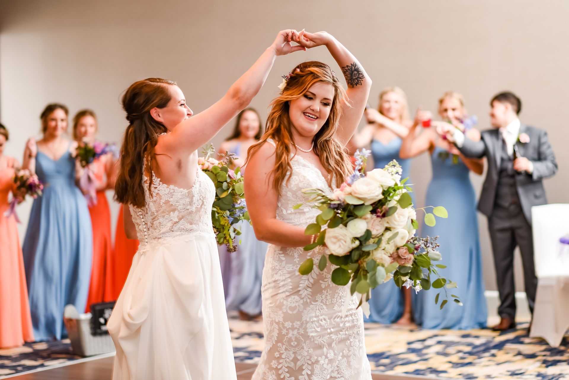 Two brides are dancing in front of their wedding party.