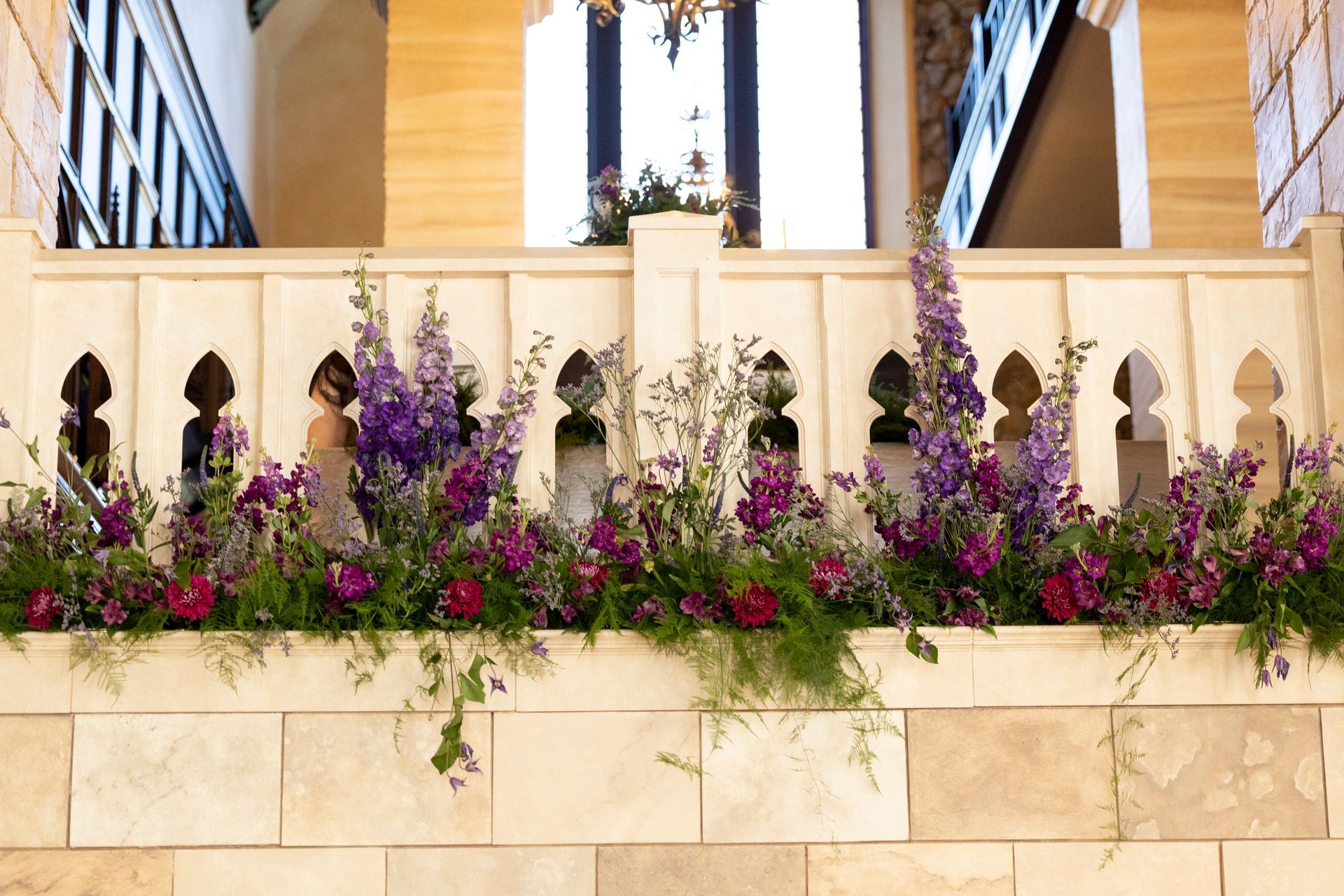 A balcony with purple flowers and greenery on it