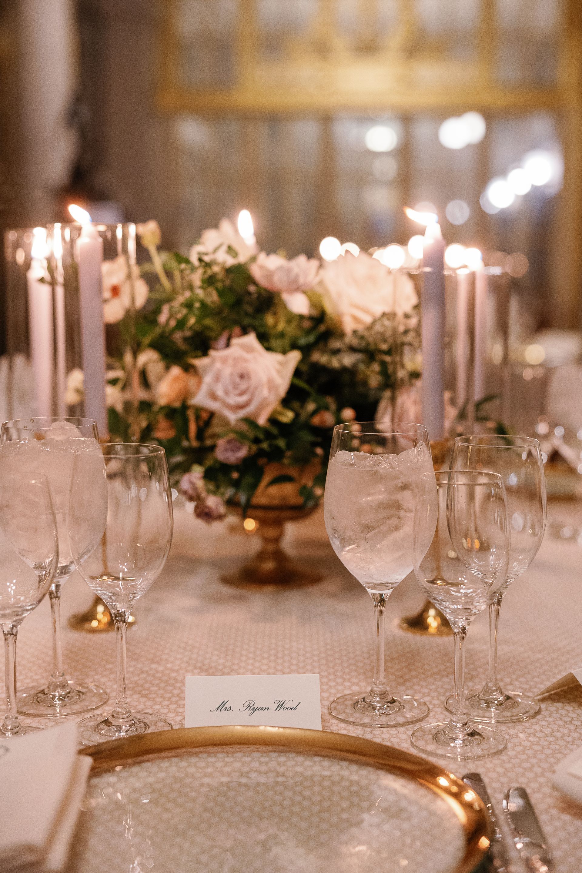 A table setting with a vase of flowers and candles on it.