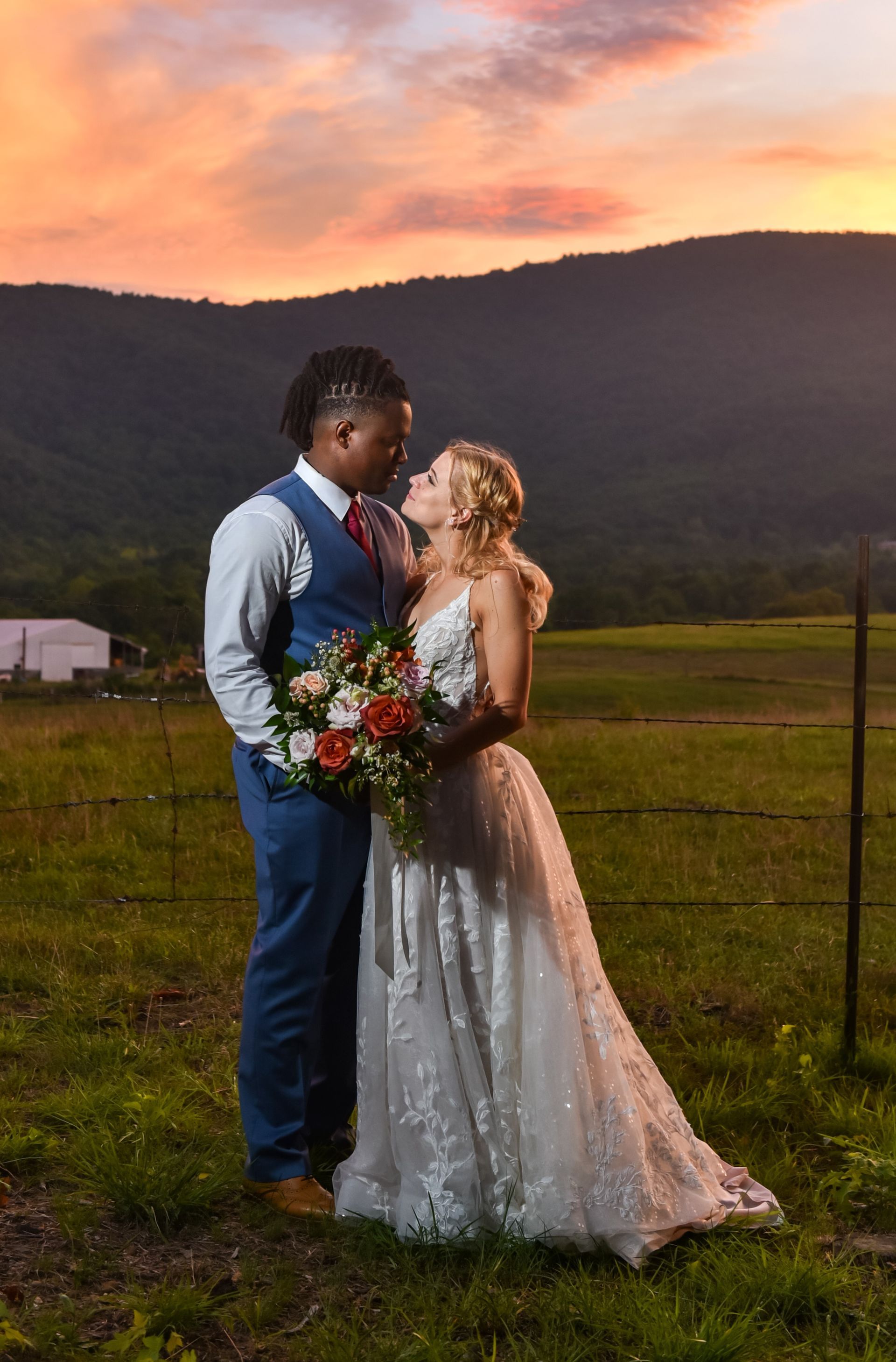 A bride and groom are looking into each other 's eyes while holding a bouquet of flowers.