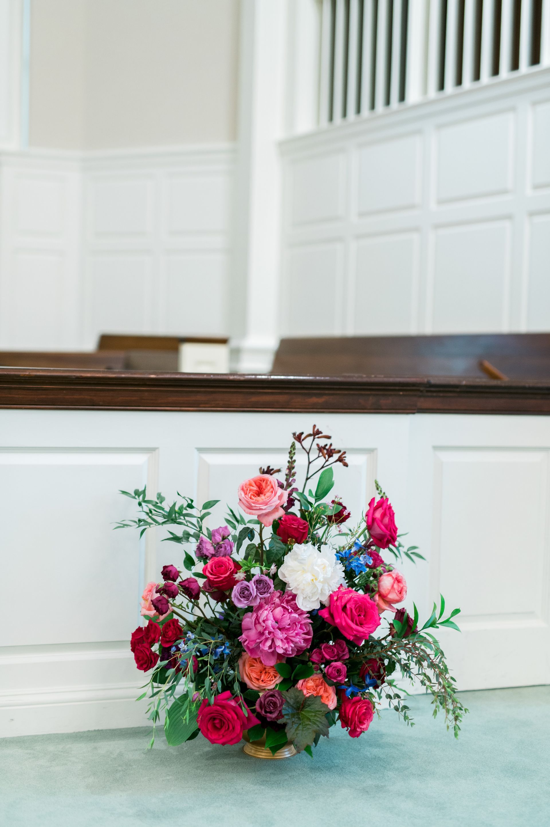 A large bouquet of flowers is sitting on the floor in a church.