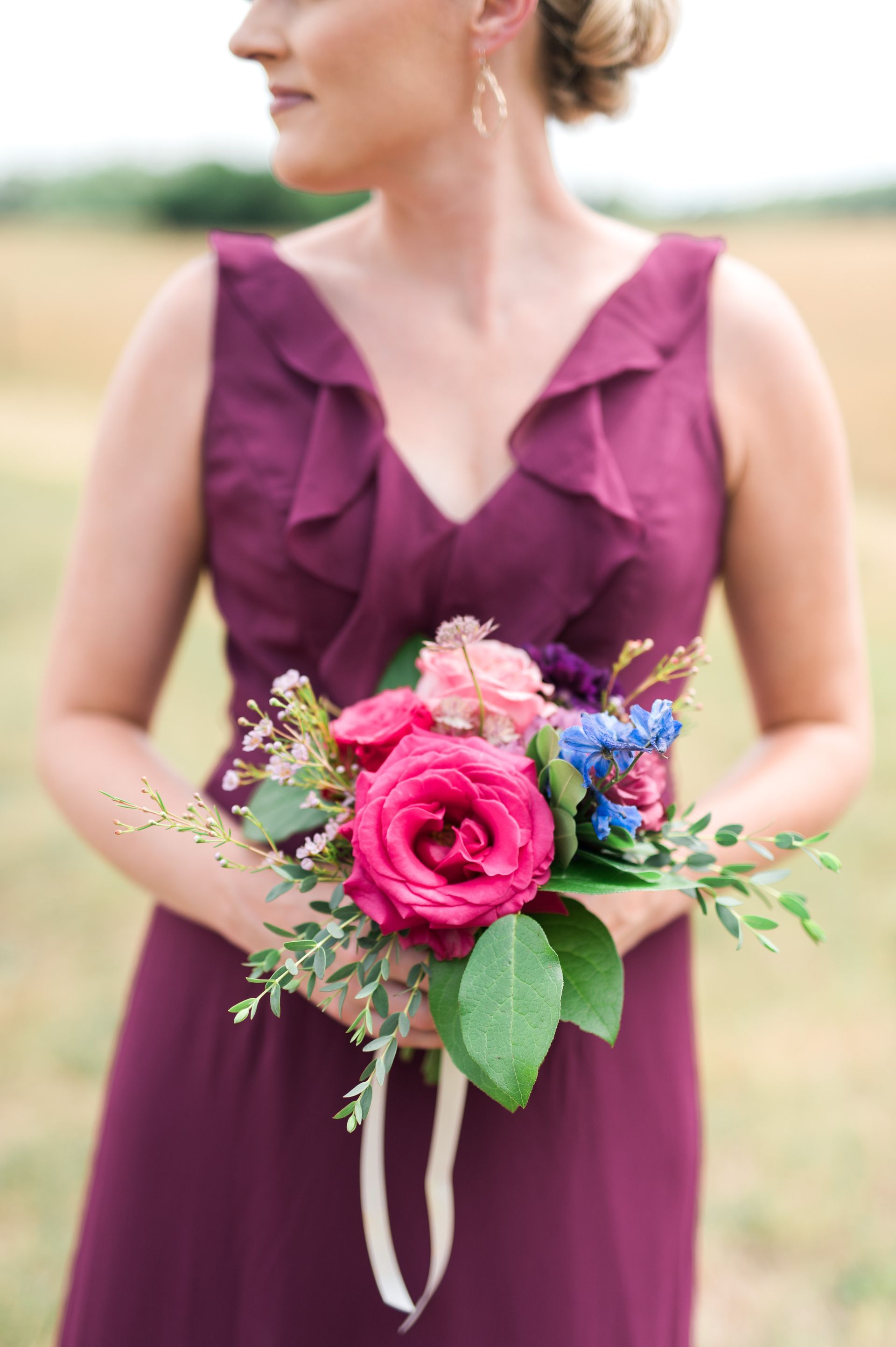 A woman in a purple dress is holding a bouquet of flowers.