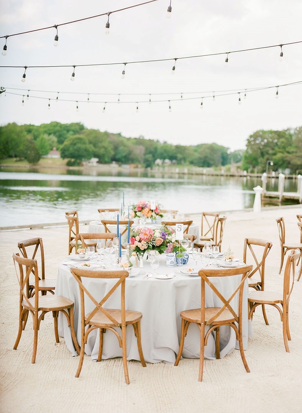 A table and chairs on the beach with a lake in the background