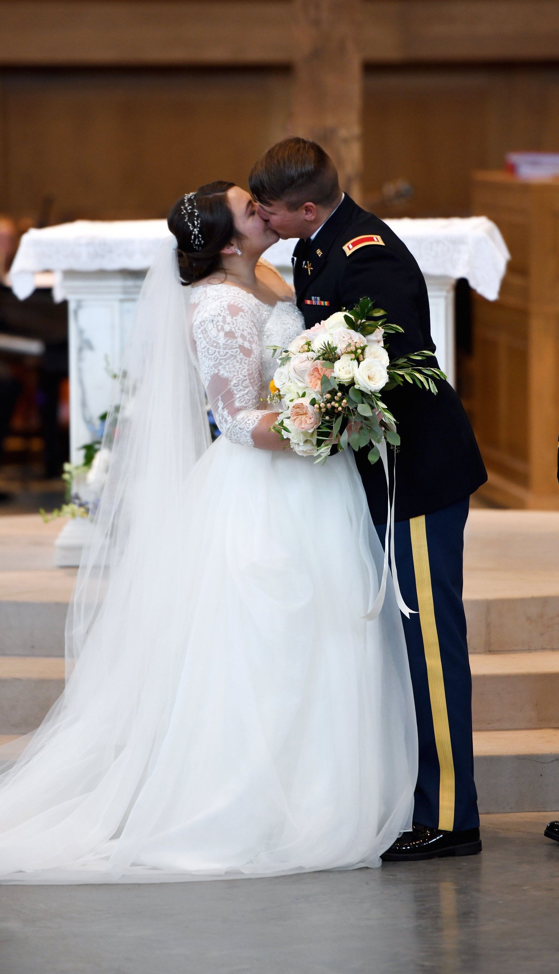 A bride and groom kissing at their wedding ceremony in a church.