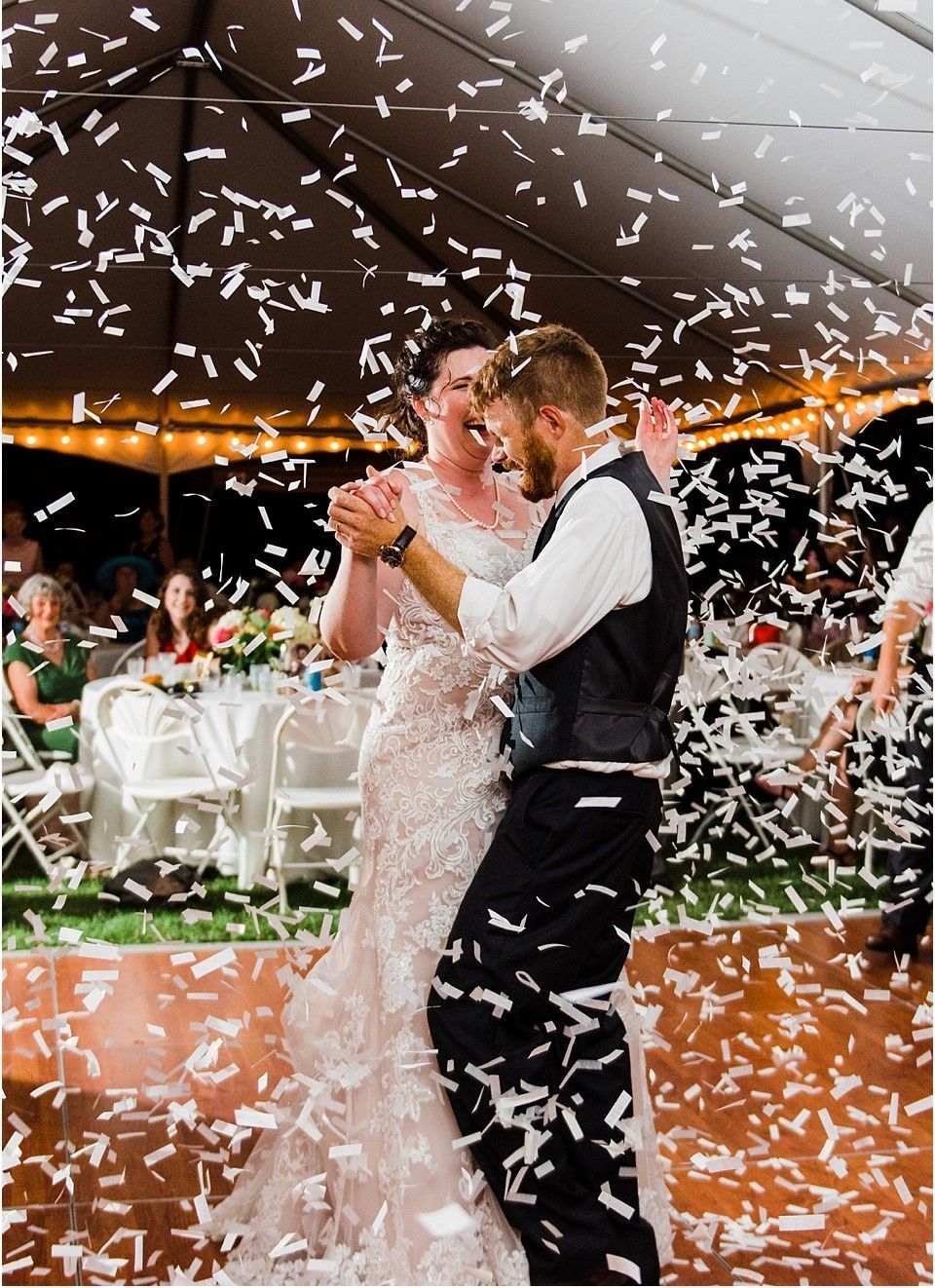 A bride and groom are dancing on a dance floor with confetti falling around them.