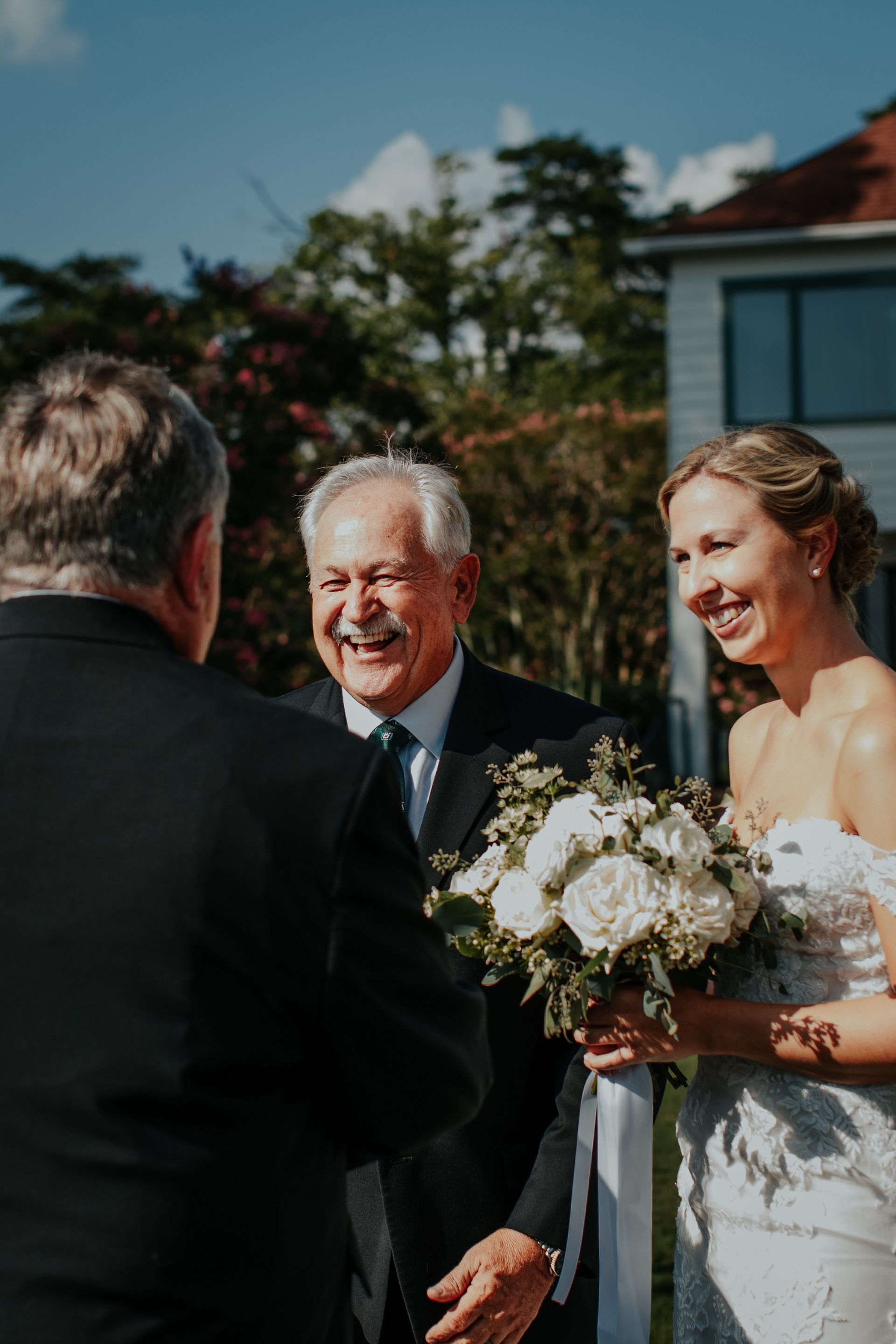 A bride and groom are laughing while standing next to each other at their wedding ceremony.