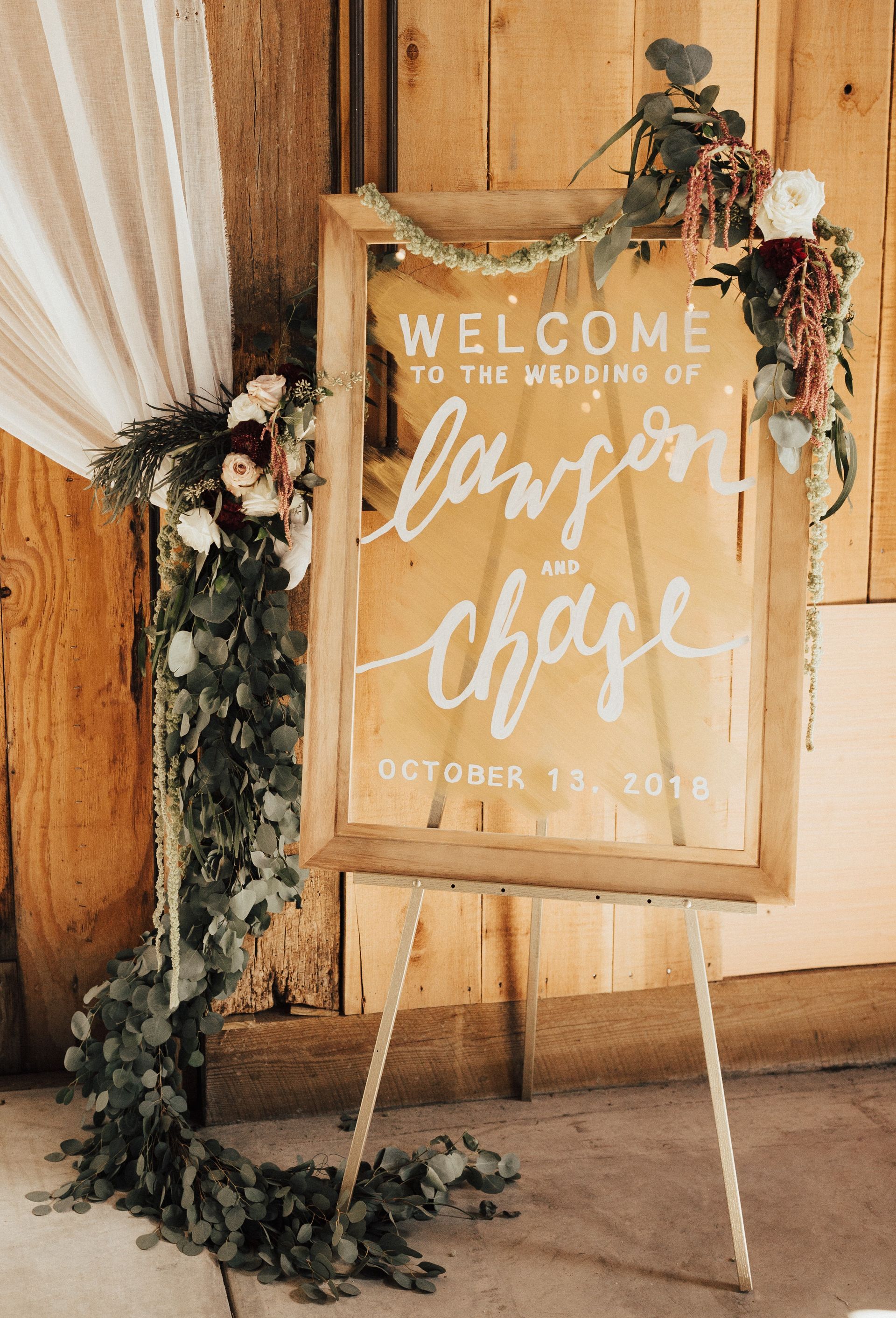 A welcome sign for a wedding is hanging on a wooden wall.