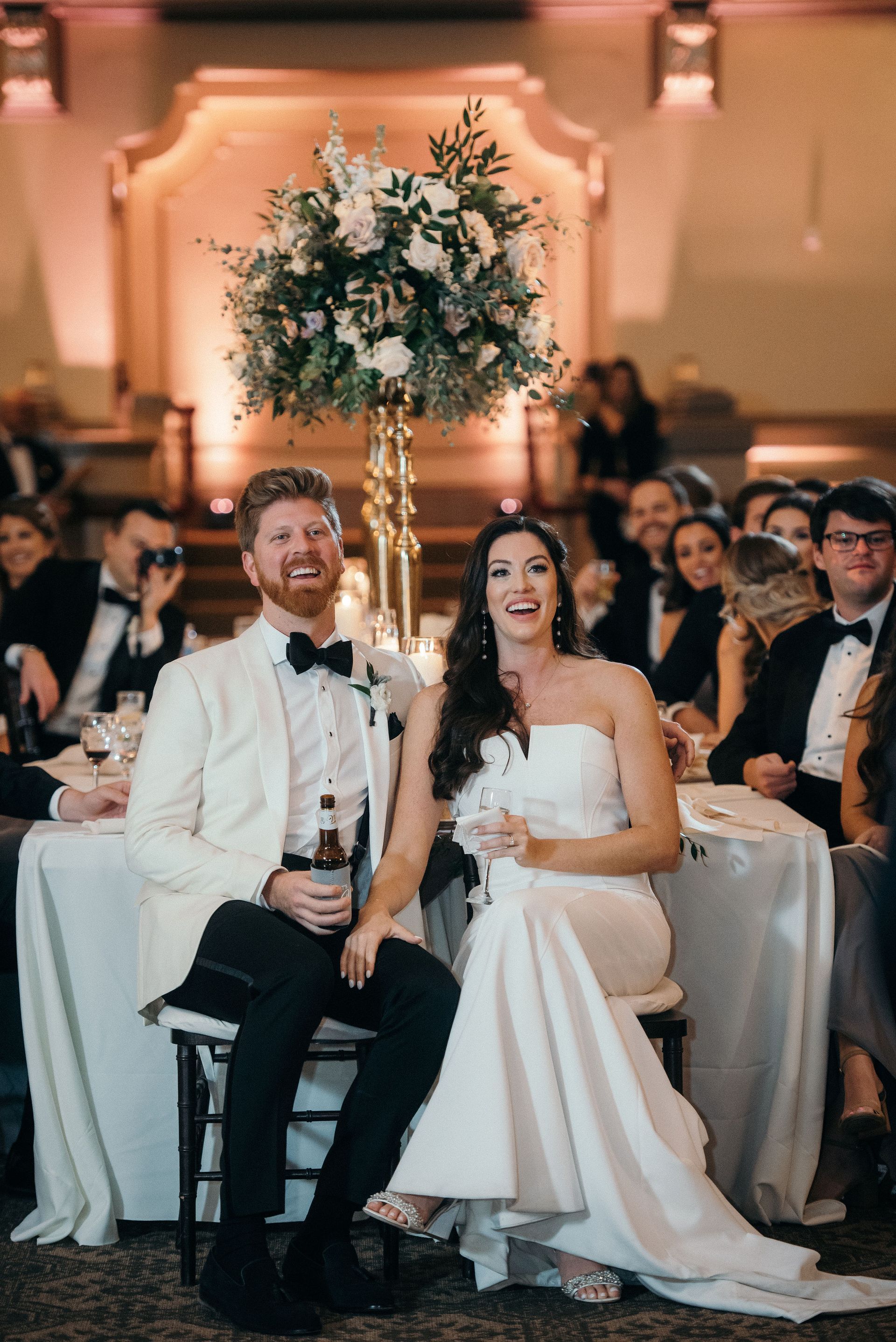 A bride and groom are sitting at a table at a wedding reception.