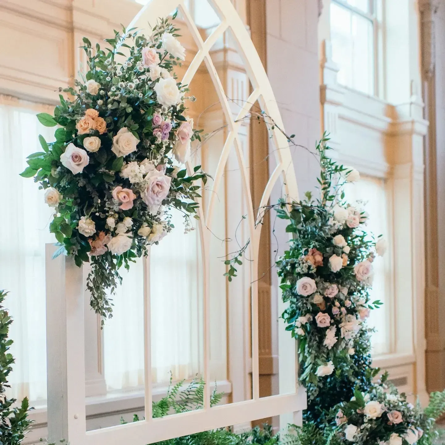 A wooden arch decorated with flowers and leaves in a room.