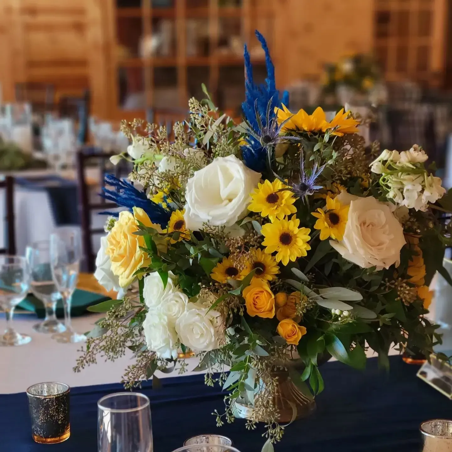 A vase filled with yellow and white flowers is on a table.