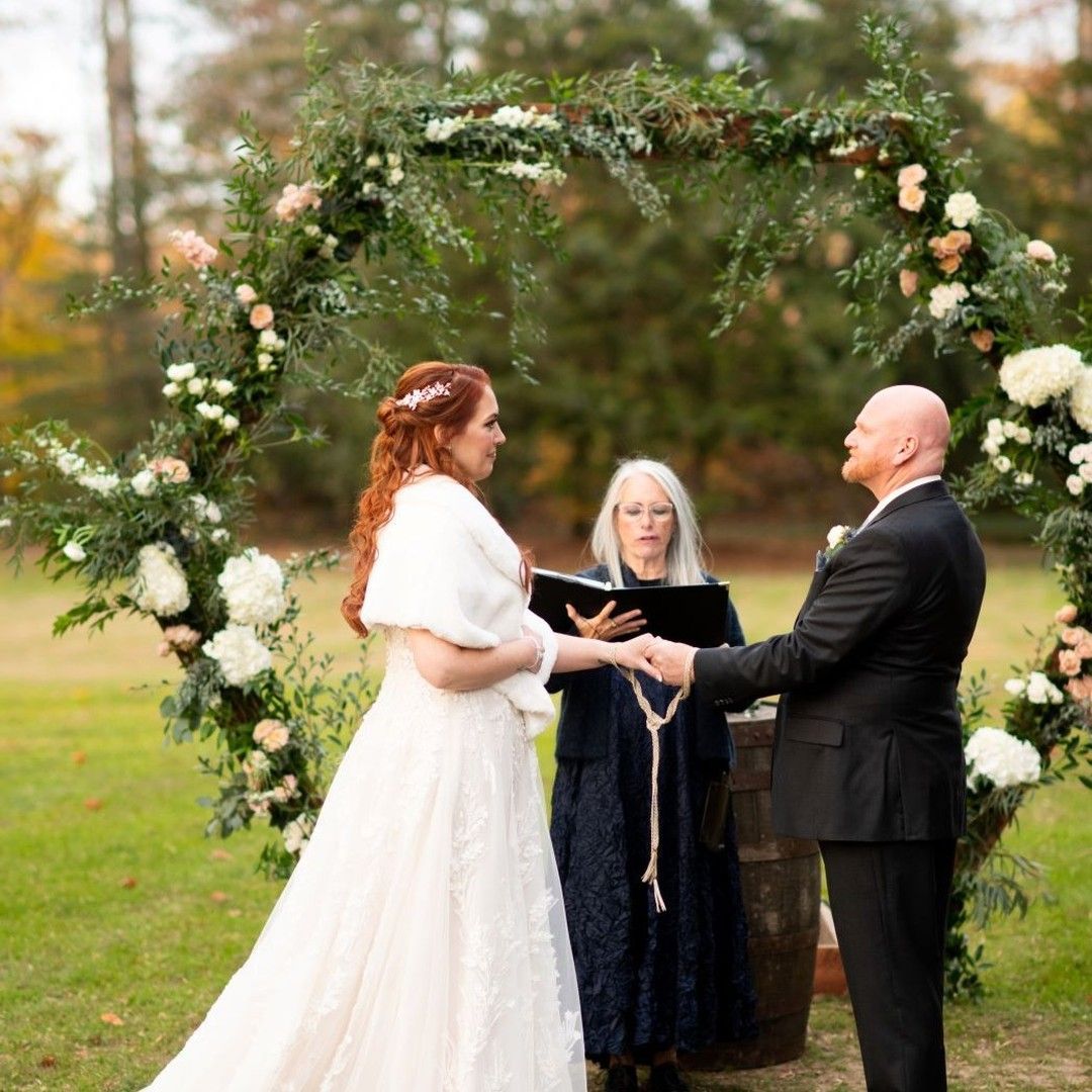 A bride and groom are holding hands during their wedding ceremony.