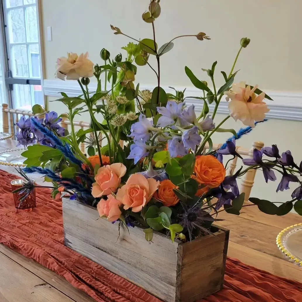 A wooden box filled with flowers sits on a table